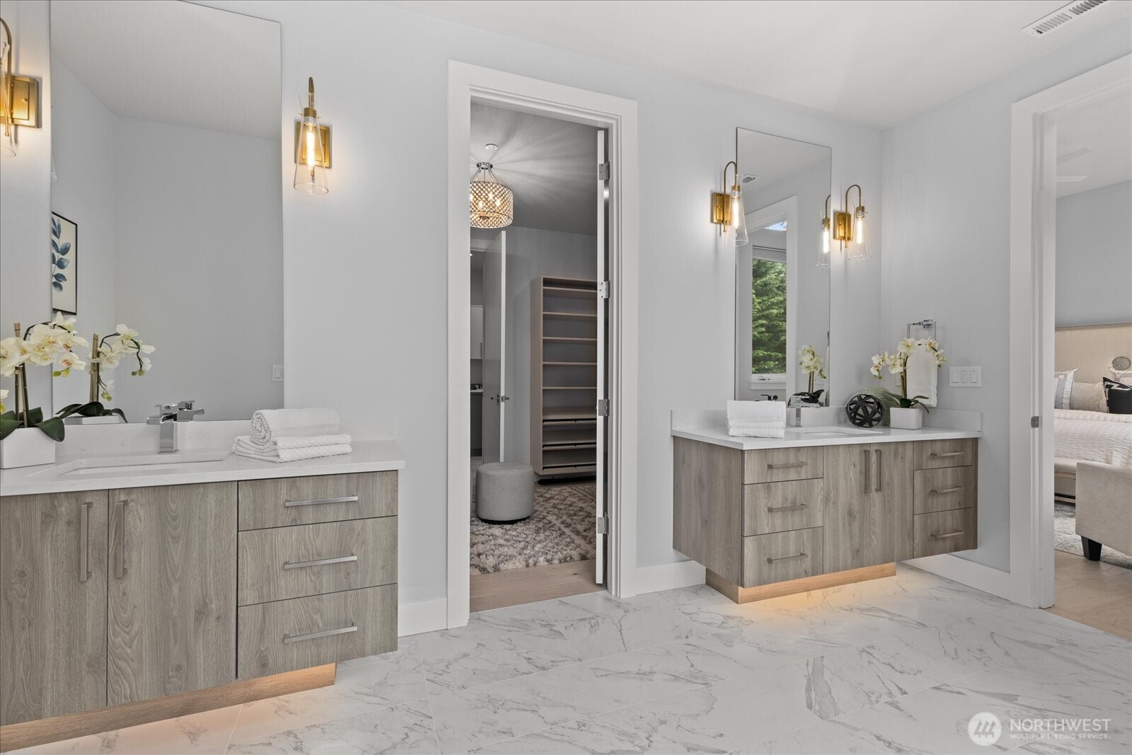Designed for everyday luxury, the primary bathroom offers dual vanities, elegant lighting, high-end finishes, and direct access to a custom dressing room for added storage, function, and ease in this Kirkland North Rose Hill luxury home.