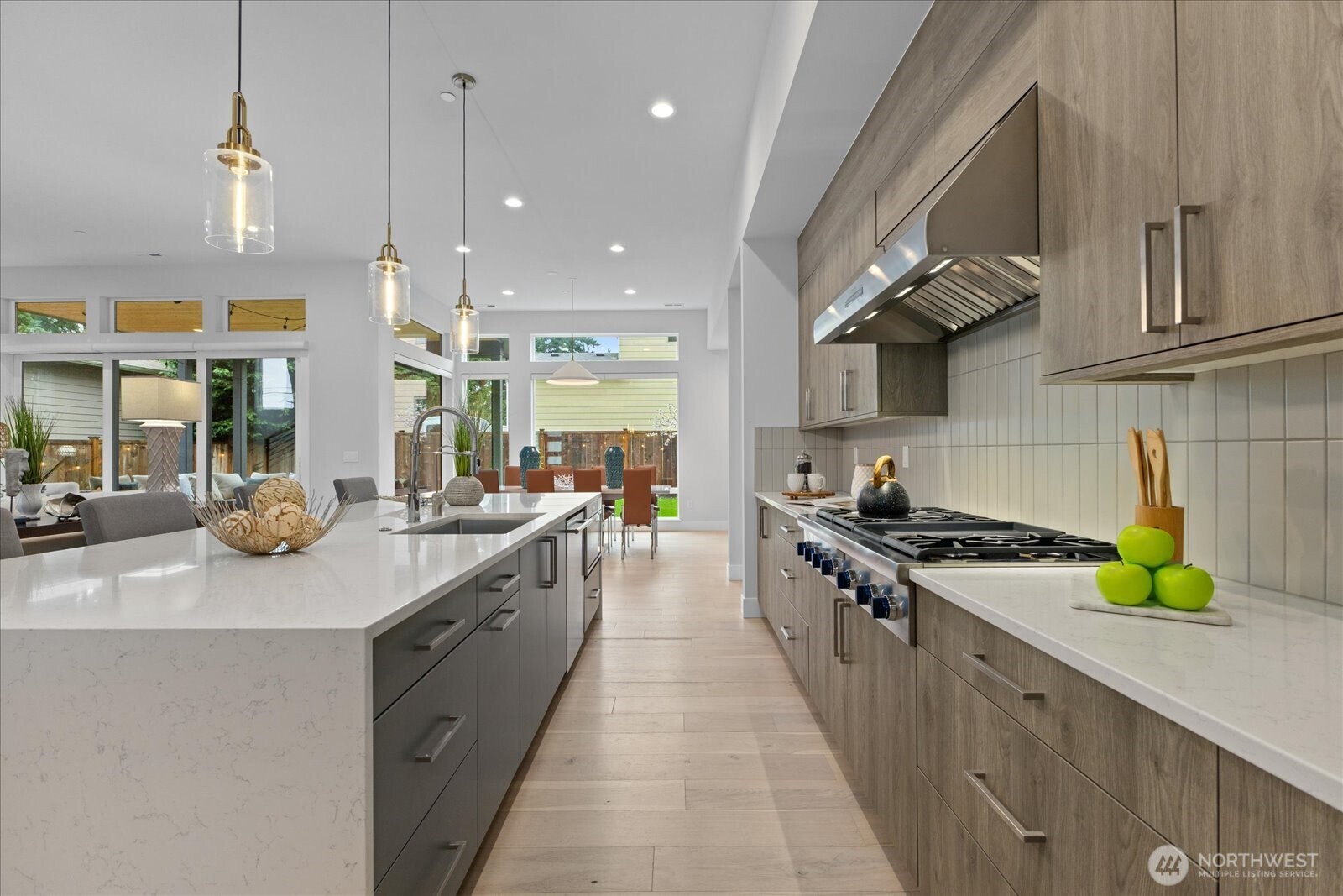 The chef’s kitchen blends beauty and function with an oversized island, warm wood cabinetry, premium Thermador appliances, water filtration system, and effortless flow to the dining area in this Kirkland North Rose Hill luxury home.