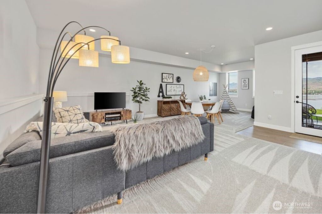 Expansive lower-level family room is wired for sound and designed for relaxed comfort, featuring incredibly plush carpeting and a calm, inviting atmosphere ideal for movie nights, games, or quiet evenings in. Glass door opens to a private lake view patio, creating seamless indoor-outdoor living and an additional space to unwind and enjoy the Chelan scenery.