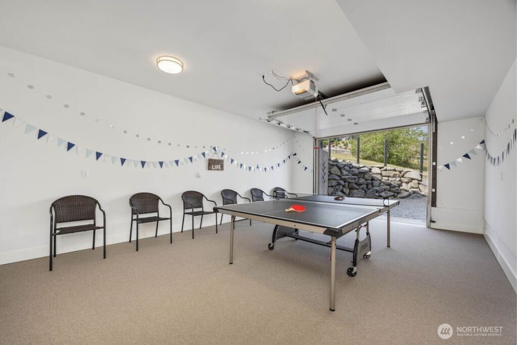 Fully finished lower-level third-car garage is currently utilized as a recreation space with room for ping pong, games, workouts, or flexible entertaining. Garage door creates an adaptable four-season indoor-outdoor environment, expanding the functionality of this unique bonus space.