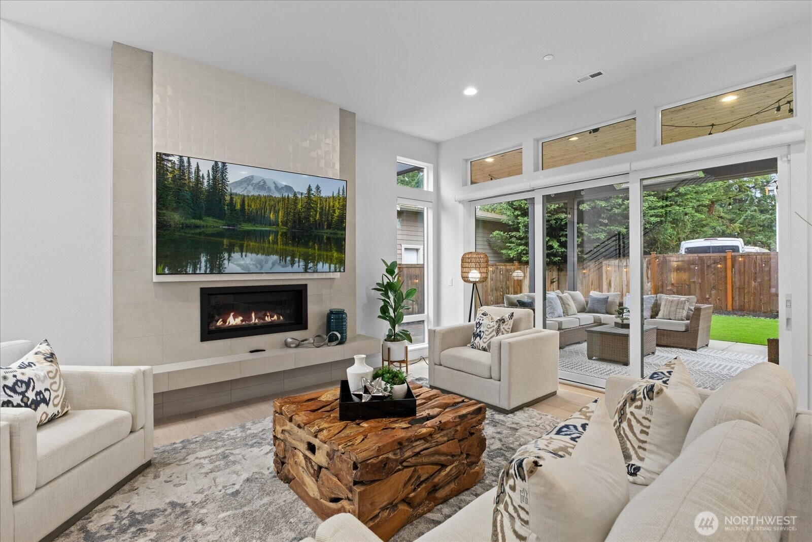 The great room is framed by soaring windows, a striking fireplace, and abundant natural light, with seamless indoor-outdoor flow to the covered patio in this Kirkland North Rose Hill luxury home.