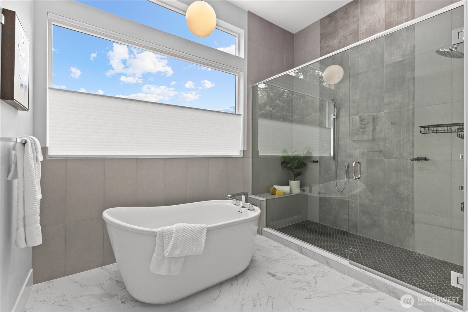 The spa-inspired primary bath features a sculptural soaking tub, oversized walk-in shower, serene finishes, and a luxurious design that creates a private retreat in this Kirkland North Rose Hill home.