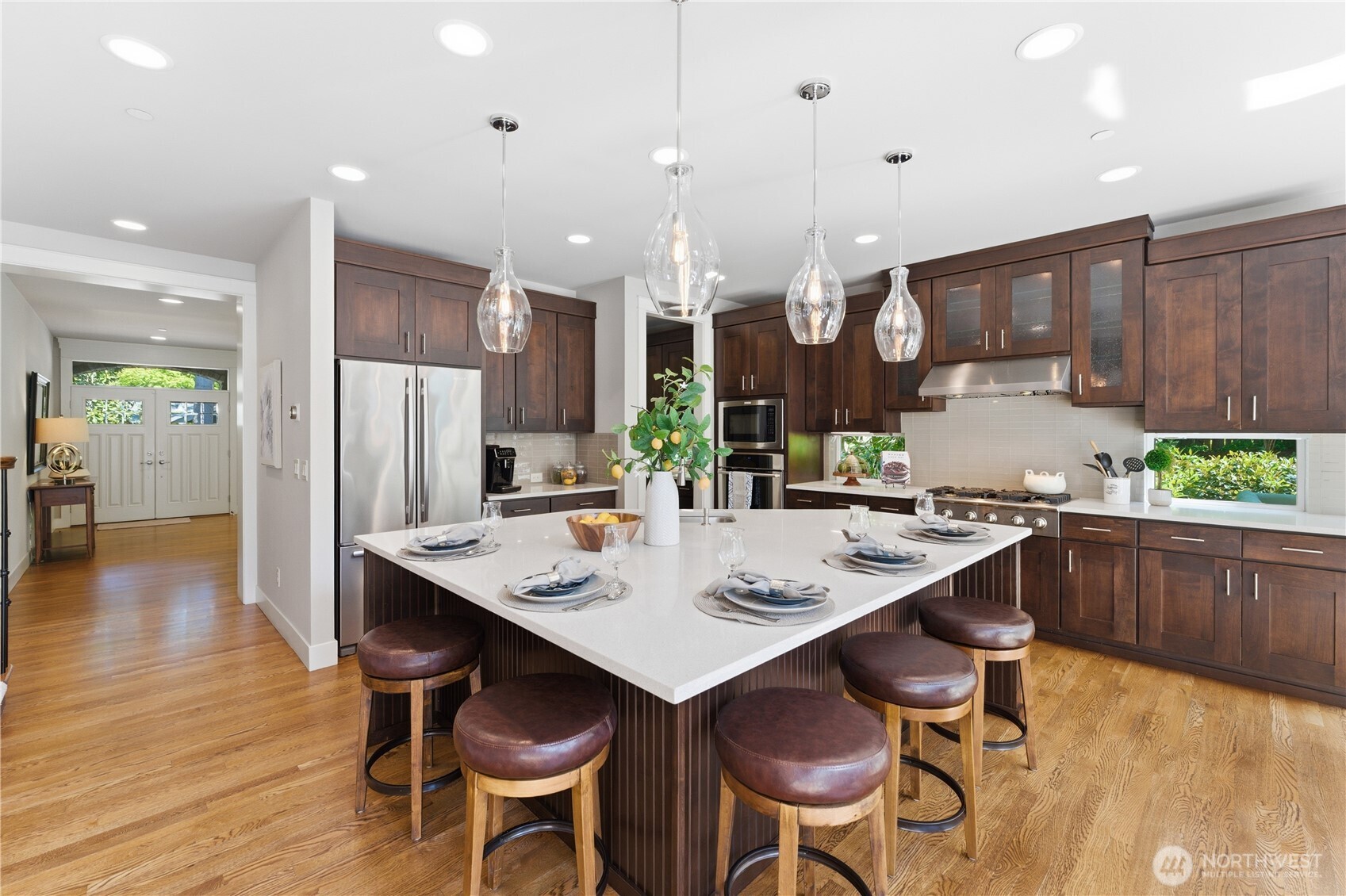 Gather around the grand island with seating for six and warm pendant lighting. Stainless-steel appliances stay, and the coffee bar and low windows frame peaceful garden views