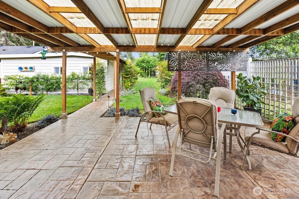 Covered patio area with stamped concrete overlooks the lush backyard with loads of fruit options!