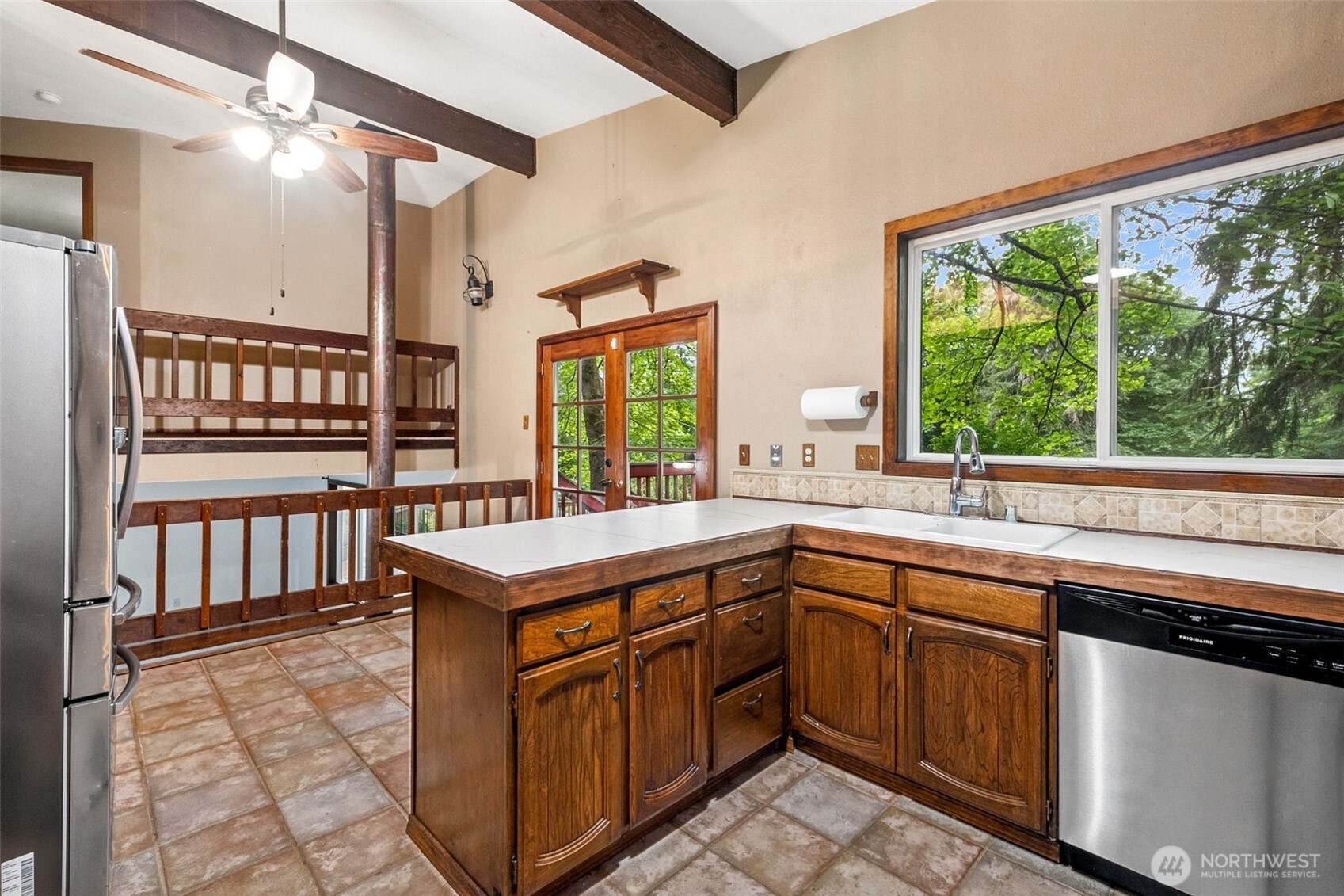 Kitchen has some upgrades, with stainless appliances and newer laminate counters. Beautiful wood beams overhead add character to the space. Wood french doors lead to the outside upper deck, and peak views from the kitchen windows.