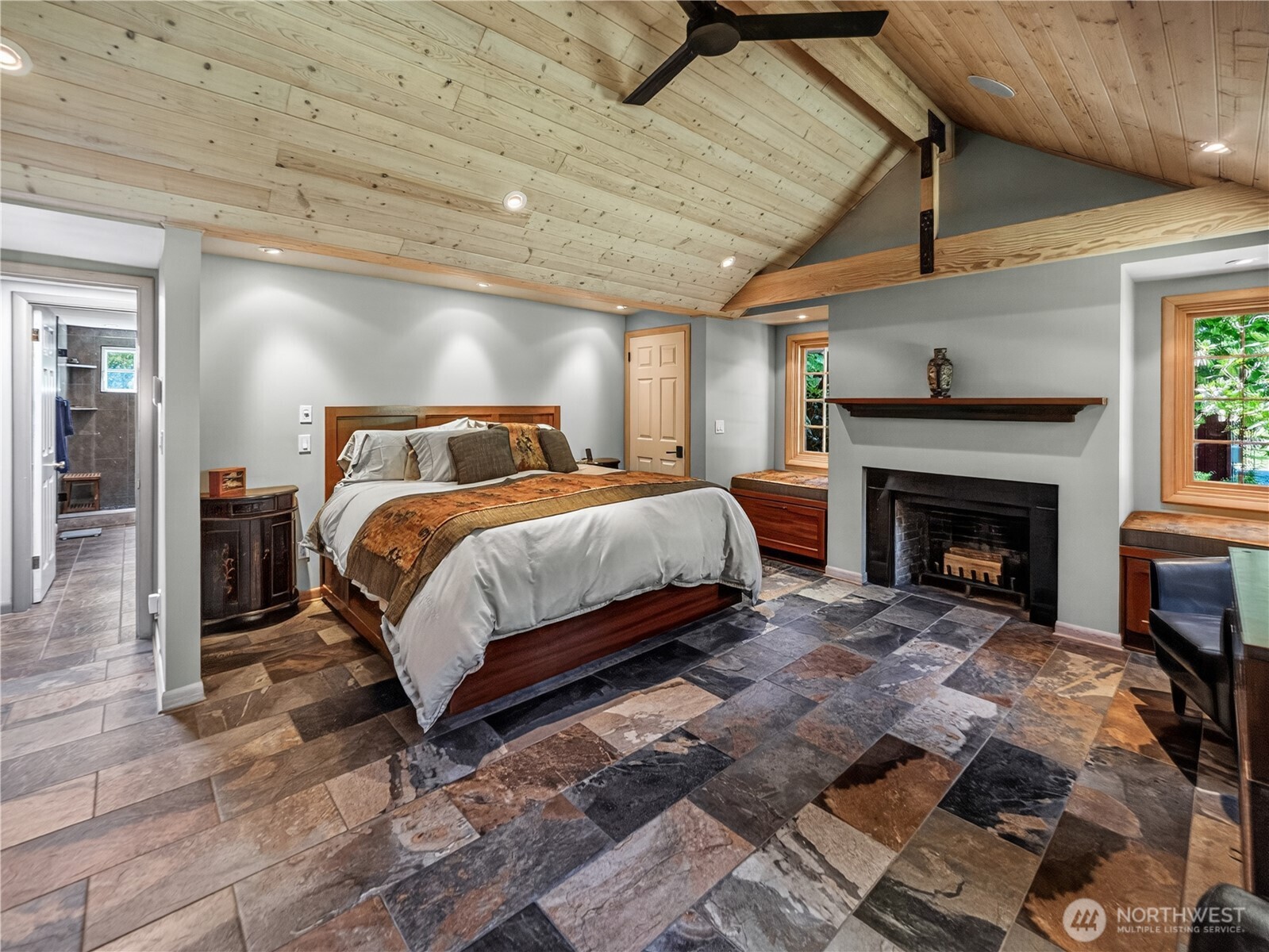 Primary bedroom with vaulted ceilings, heated tile floors, & a wood fireplace.