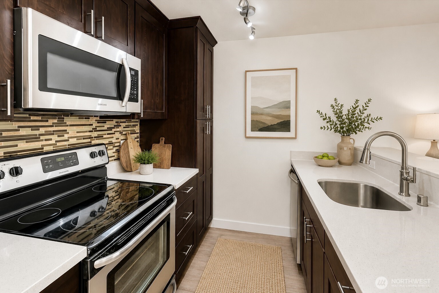 The upgraded galley kitchen features quartz countertops, a breakfast bar, stainless steel appliances.