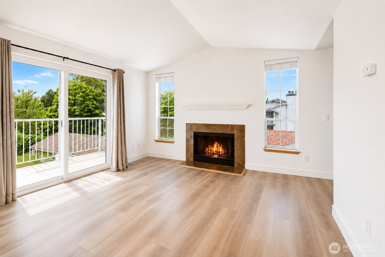 The sunny and spacious living room features vaulted ceilings and a cozy fireplace.