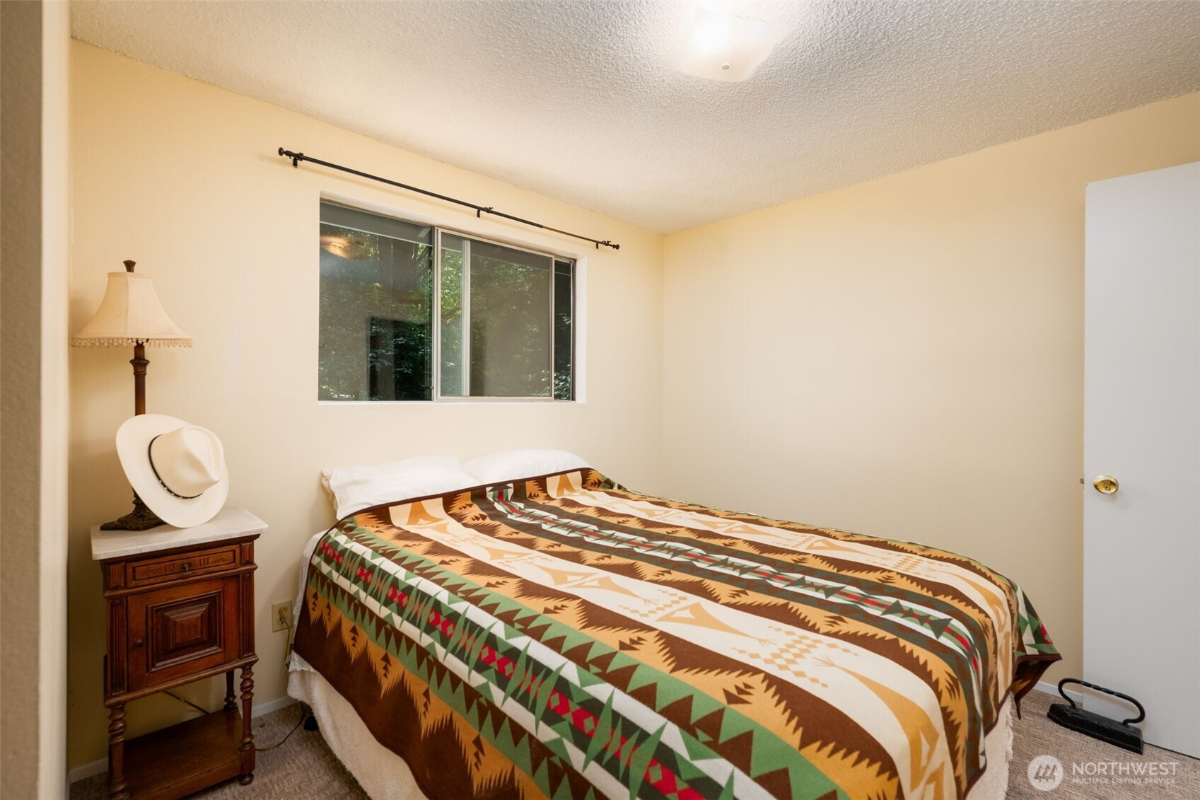 The second bedroom has able space for a queen sized bed and looks off into the front yard full of trees keeping it cool in the summer!