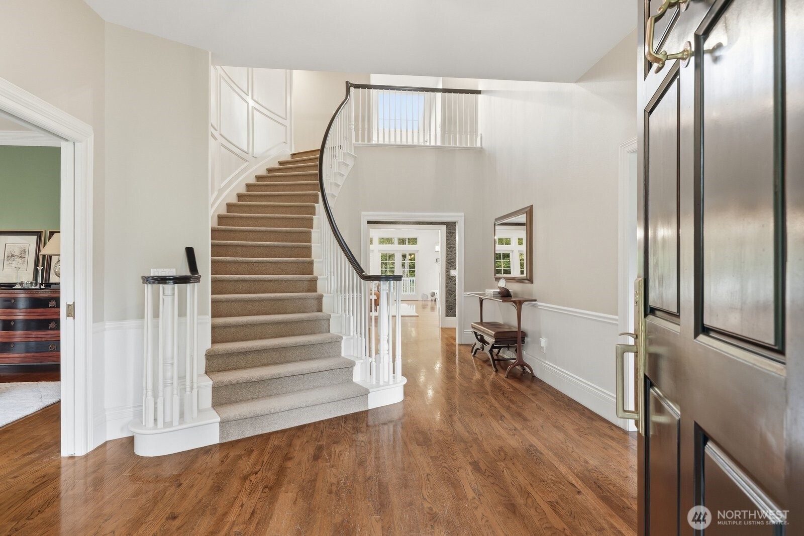 Classic Colonial architecture with formal rooms flanking the foyer with curved stairway with a wall of elegant shadow box moldings.