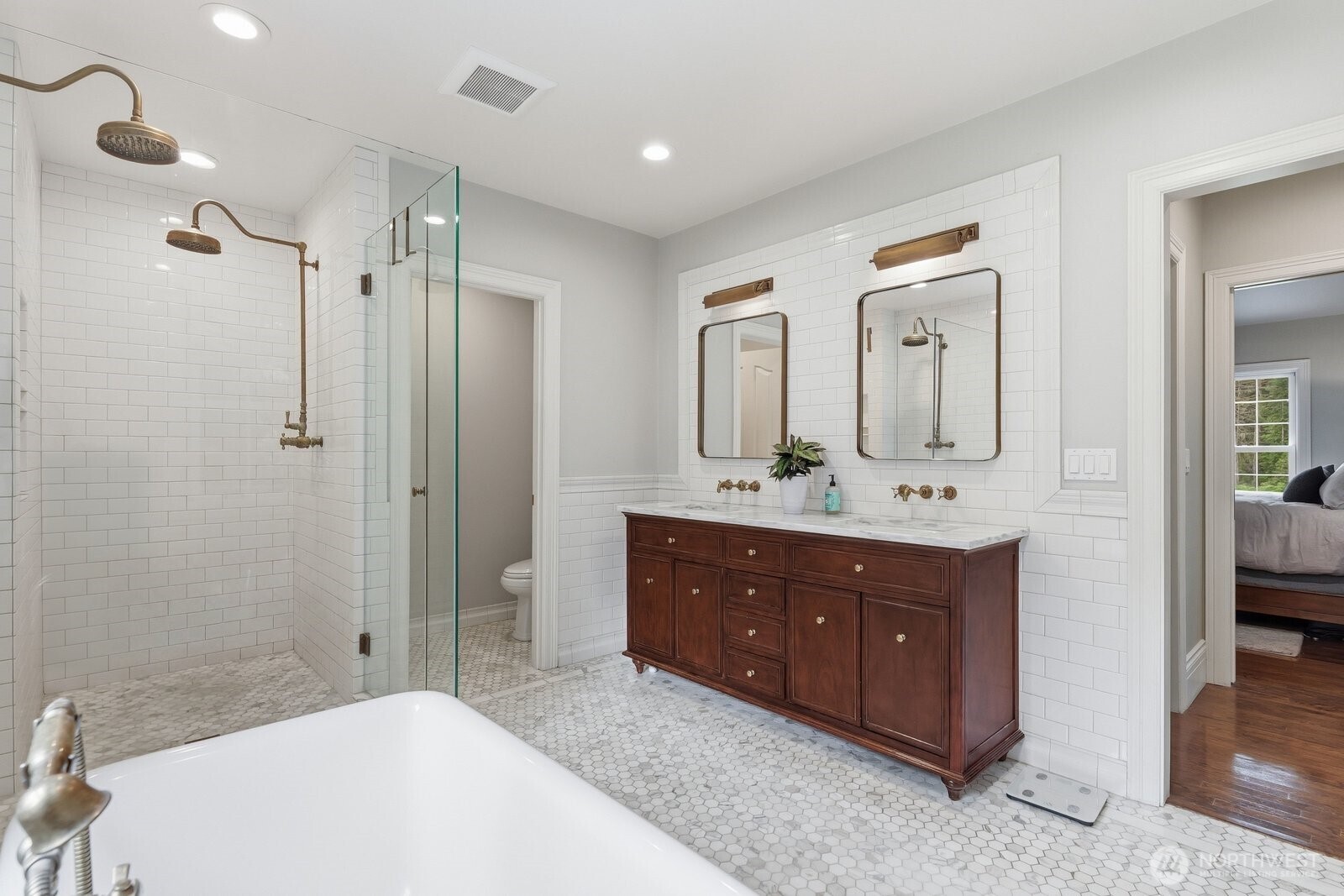 Spa-inspired Carrara marble bath adorned with European antique brass fixtures and heated marble floors.