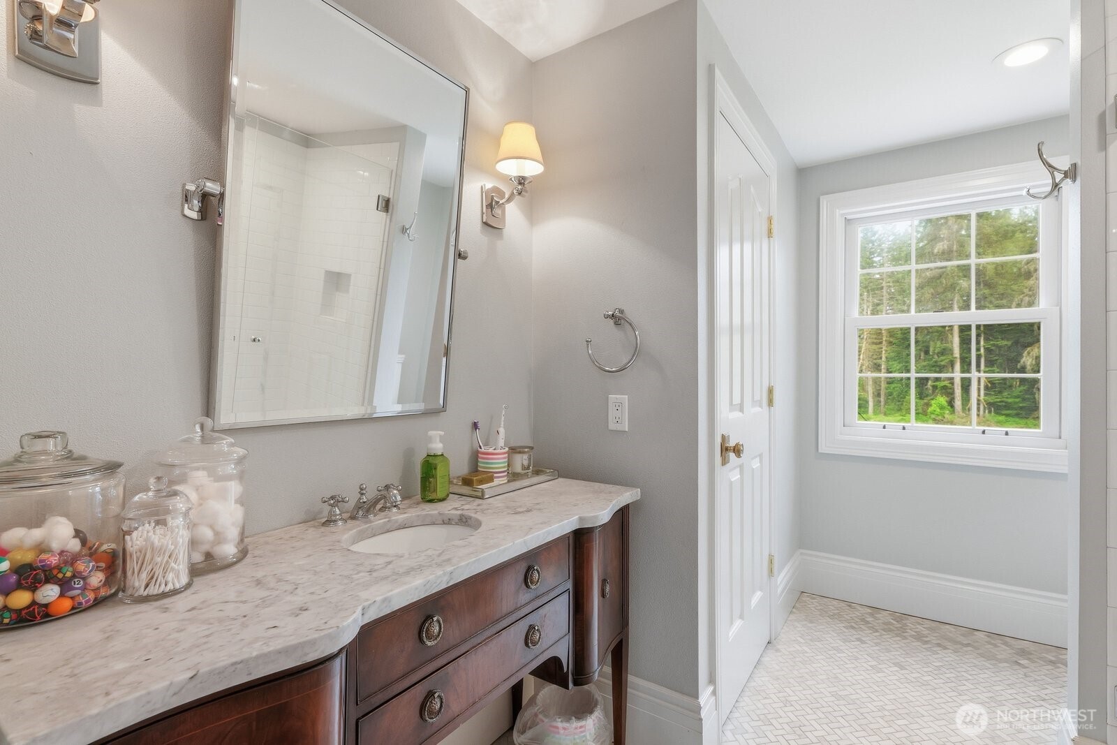 The 3/4 bathroom in this bedroom with marble vanity and floor, sconce lighting and linen closet.