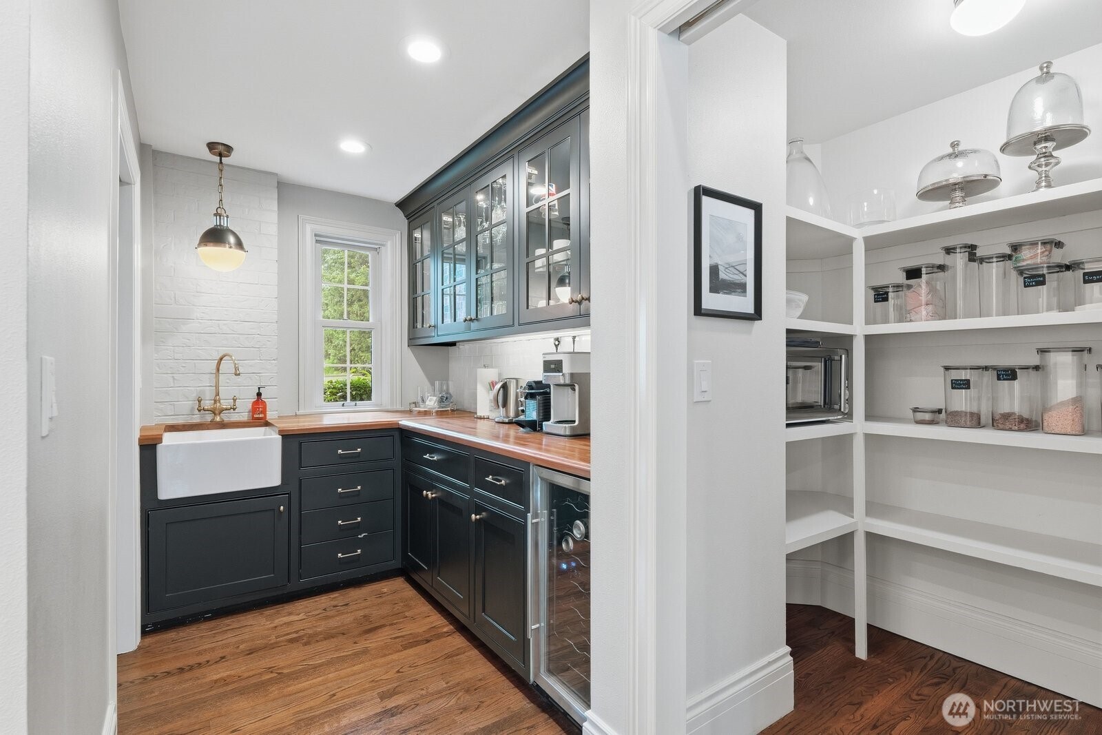 Beautifully appointed butler’s pantry with farm sink and beverage fridge. The large pantry area for the kitchen nearby.