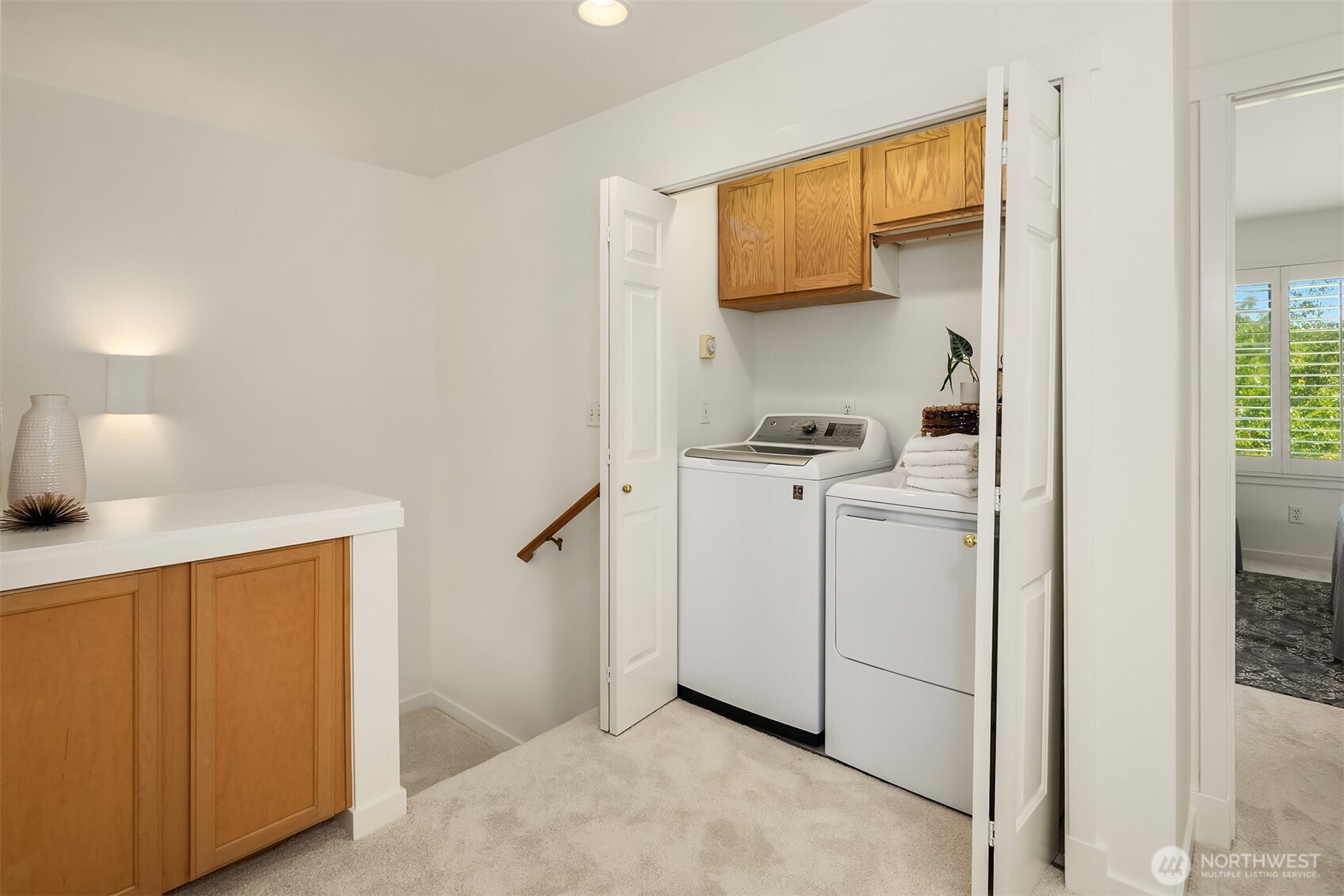 Heading up the stairs, you'll come to this landing where the washer dryer is located, a linen cupboard, and access to the secondary bedroom with adjacent full bath and primary ensuite.