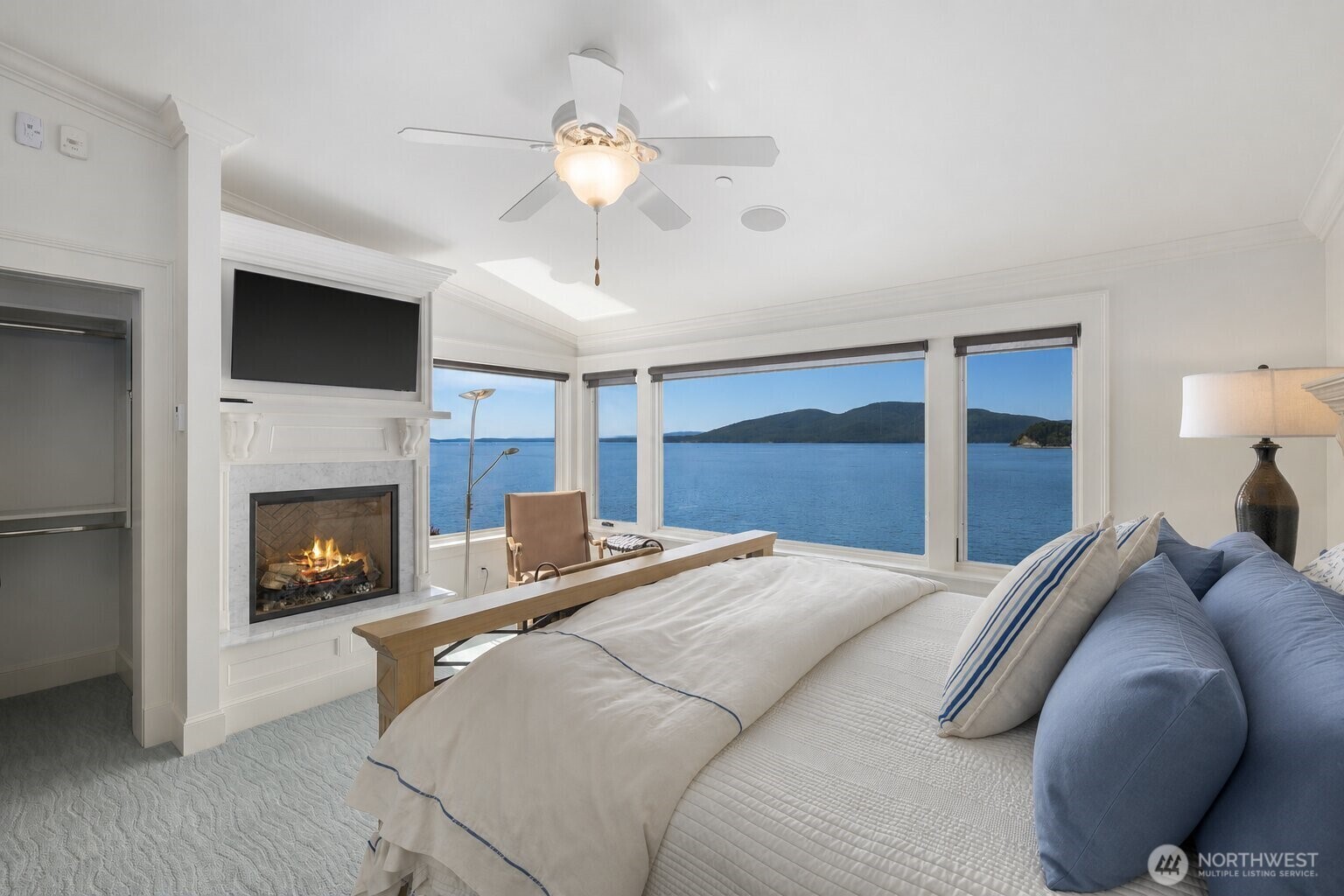Guests will wake to panoramic waterfront views in this spacious bedroom, complete with a fireplace and serene sitting area.