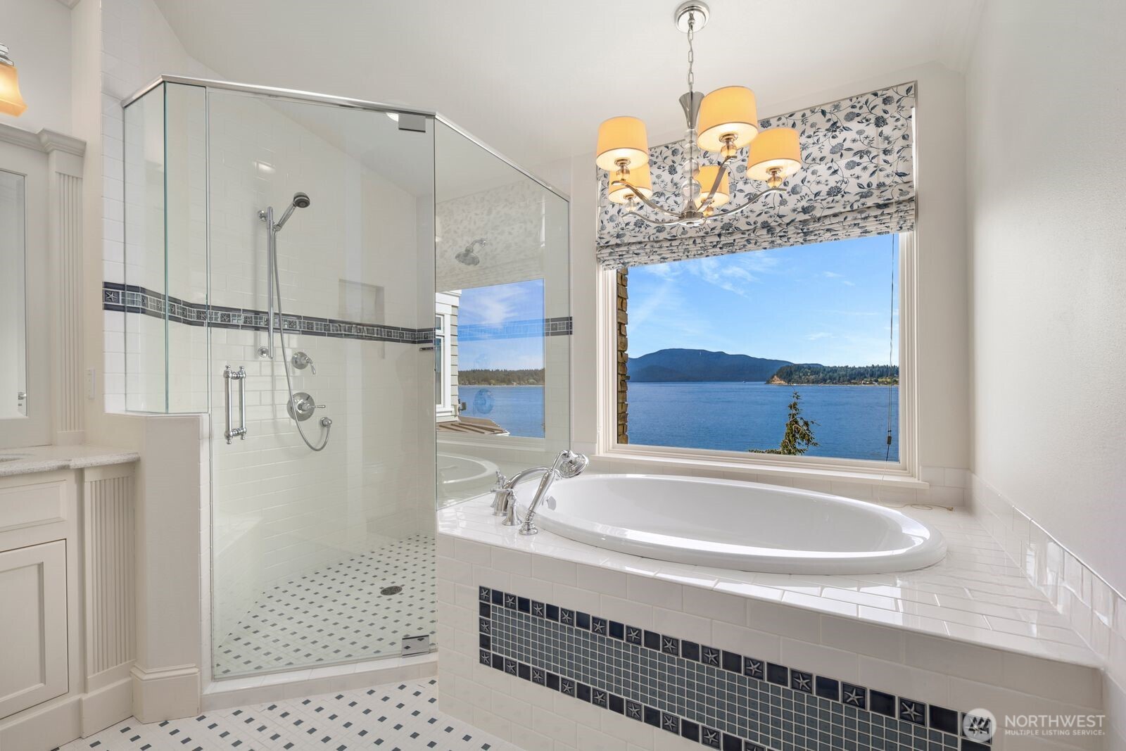 The adjoining guest bath creates a spa-like experience with a soaking tub perfectly positioned to capture breathtaking waterfront views.