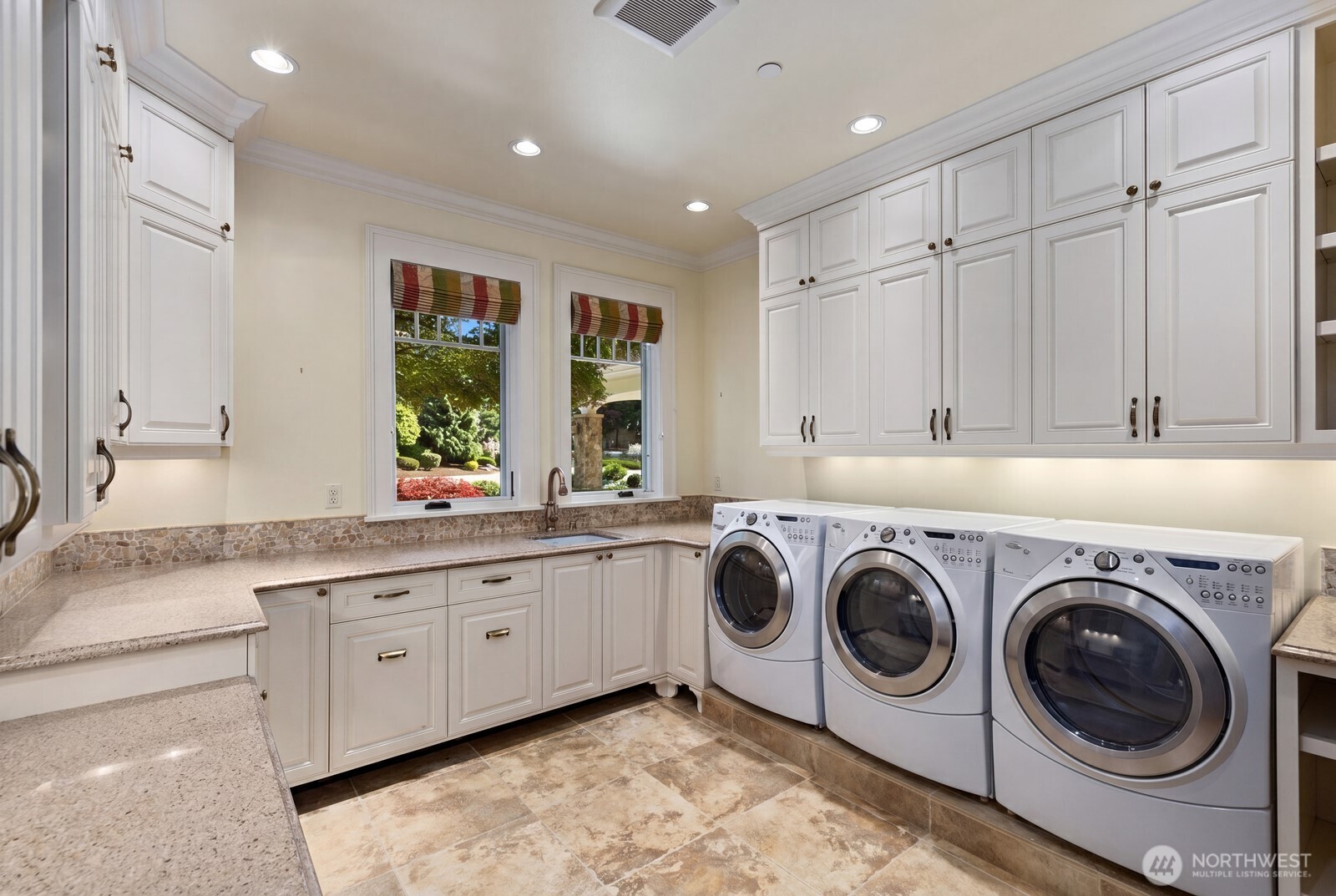 The spacious laundry room is thoughtfully designed with abundant cabinetry, generous counter space, and room to keep everyday living effortlessly organized.
