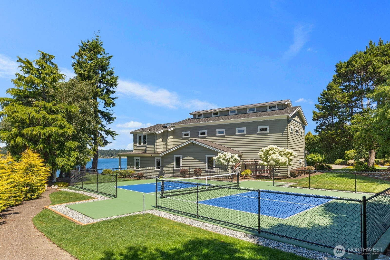 Enjoy resort-style living with a private pickleball court set against the backdrop of beautifully landscaped grounds and the Salish Sea beyond.