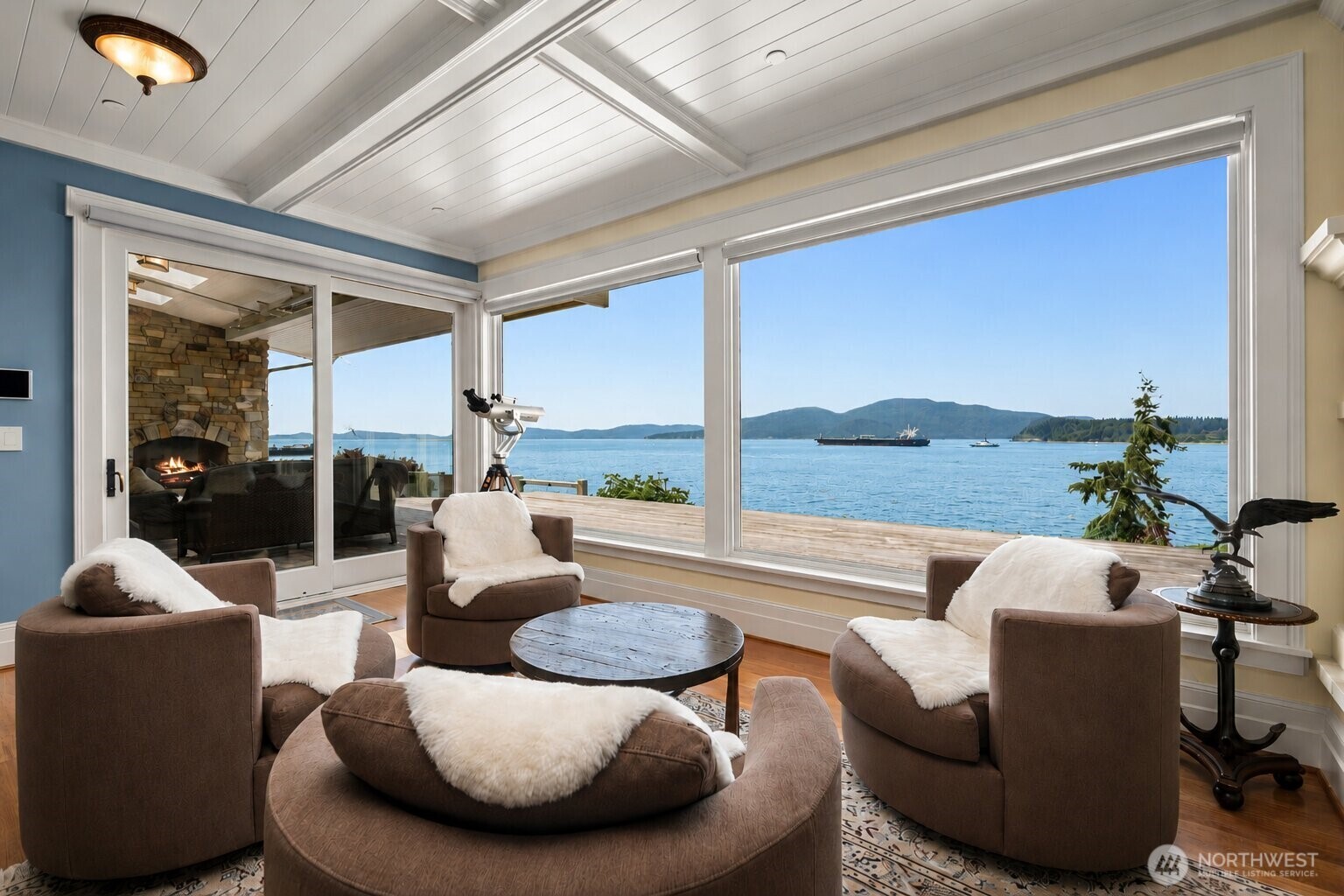Covered outdoor living extends the home's entertaining space with a fireplace, comfortable heated seating, and year-round waterfront enjoyment.