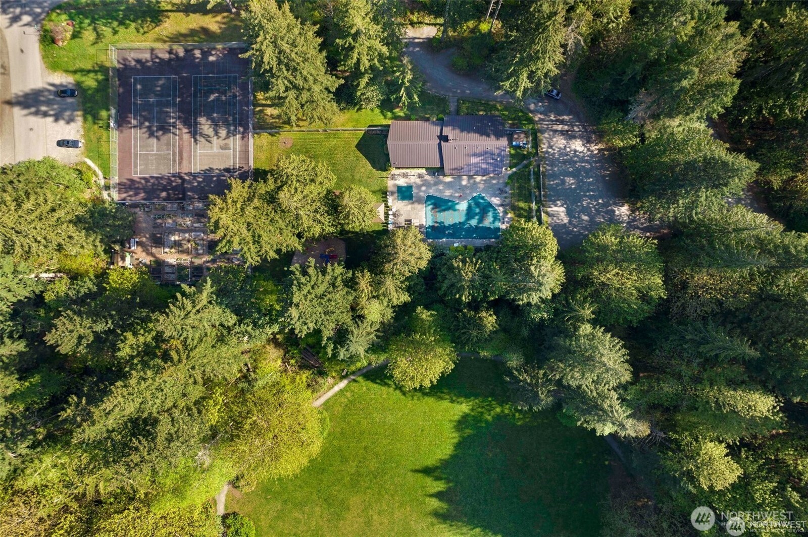 Drone shot showing the pool, tennis courts, pea patch, park area.