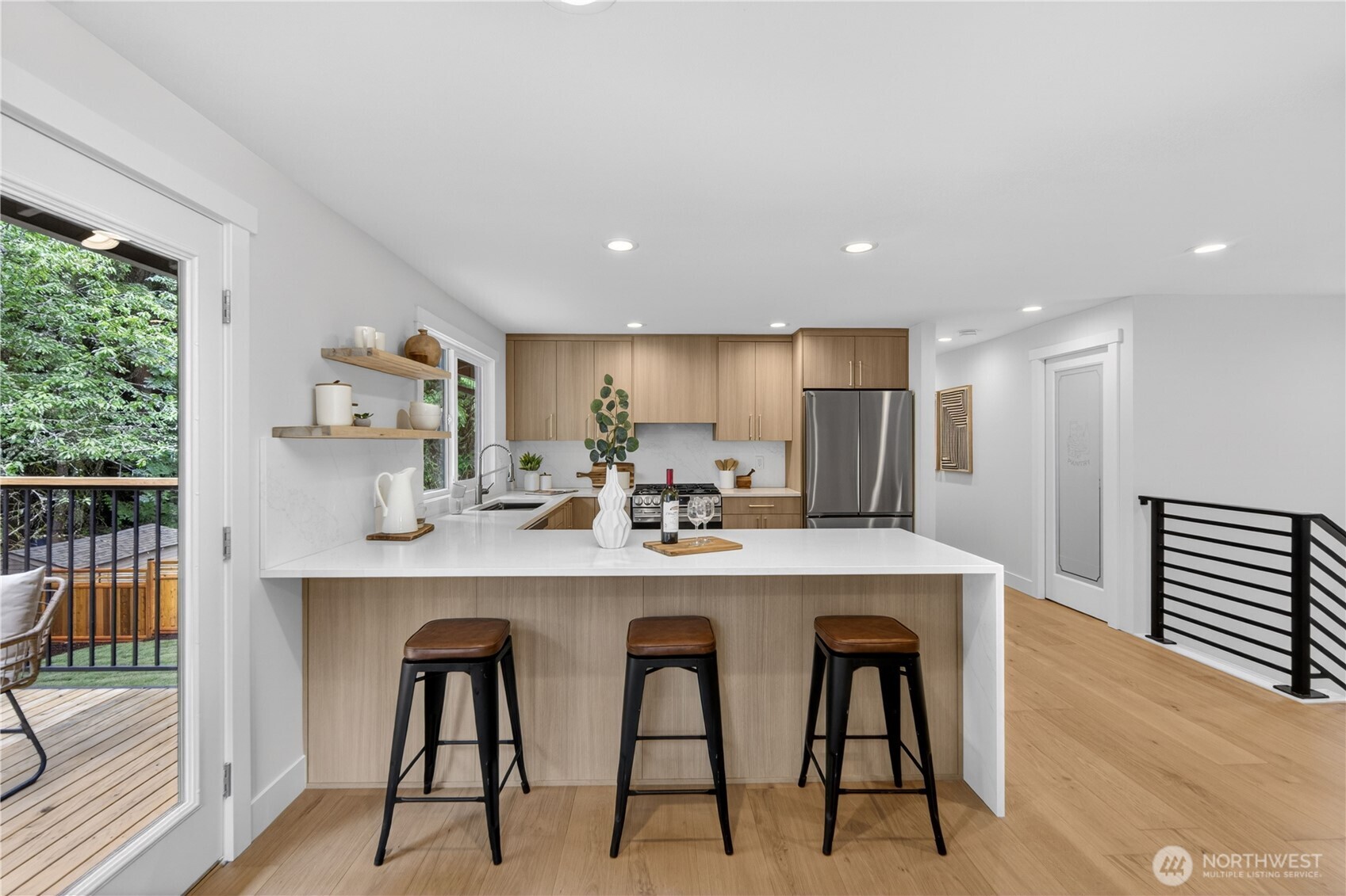 Busy mornings feel easier with a generous breakfast bar for quick meals, coffee, backpacks, and laptops. A nearby outlet makes it simple to plug in while answering emails or helping with homework, keeping everyday routines connected right where life naturally happens. Natural light creates a pleasant workspace, with snacks just steps away when it is time for a break. Finished wood detailing beneath the counter adds a beautiful, thoughtful touch, and the quartz surface gives even everyday work an elevated tone.