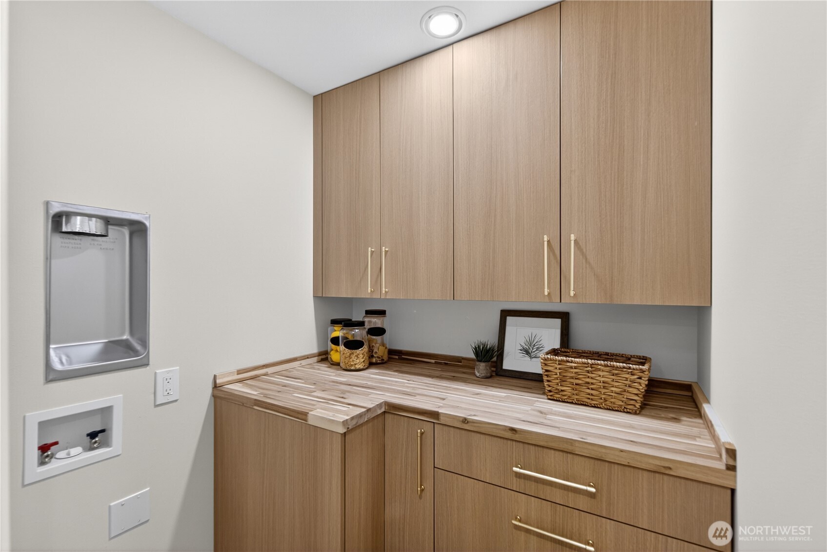 The walk-in pantry continues the same beautiful cabinetry as the kitchen for a cohesive, custom look. A butcher block-style countertop adds warmth and charm, creating a useful space for storage, prep, or small appliances, with stackable washer and dryer hookups tucked conveniently nearby, the same floor as the main bedrooms for convenience. A full size washer and drier set is downstairs as well.