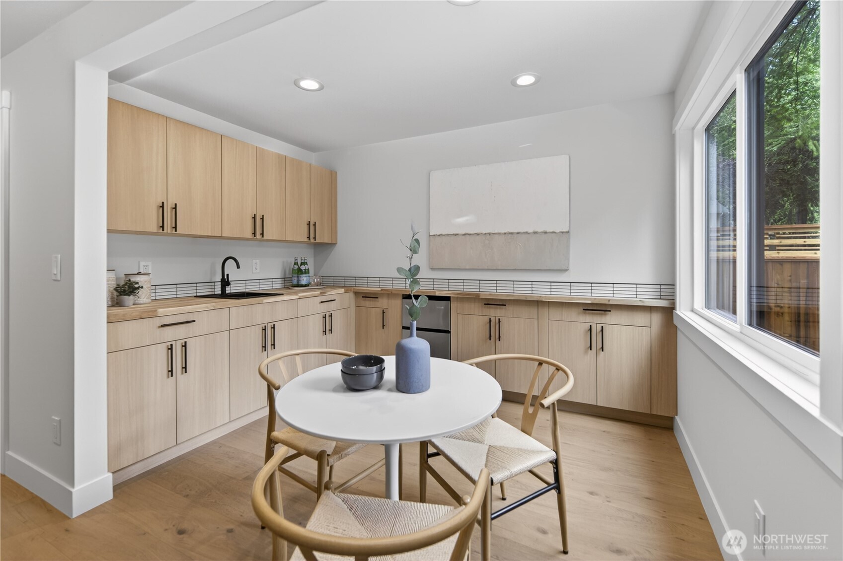 Light, fresh colors brighten the lower level kitchenette, creating a cheerful and inviting place for morning coffee or quick meals. Warm wood cabinetry, sleek black hardware, and a modern black sink echo the home’s refreshed millwork and finishes, creating a cohesive look from upstairs to downstairs. A beautiful butcher block-style counter adds warmth, the new mini fridge brings everyday convenience, and plenty of outlets make room for small appliances. With a coffeemaker and toaster oven, this kitchenette becomes an easy spot for morning coffee, quick meals, and a little extra independence.