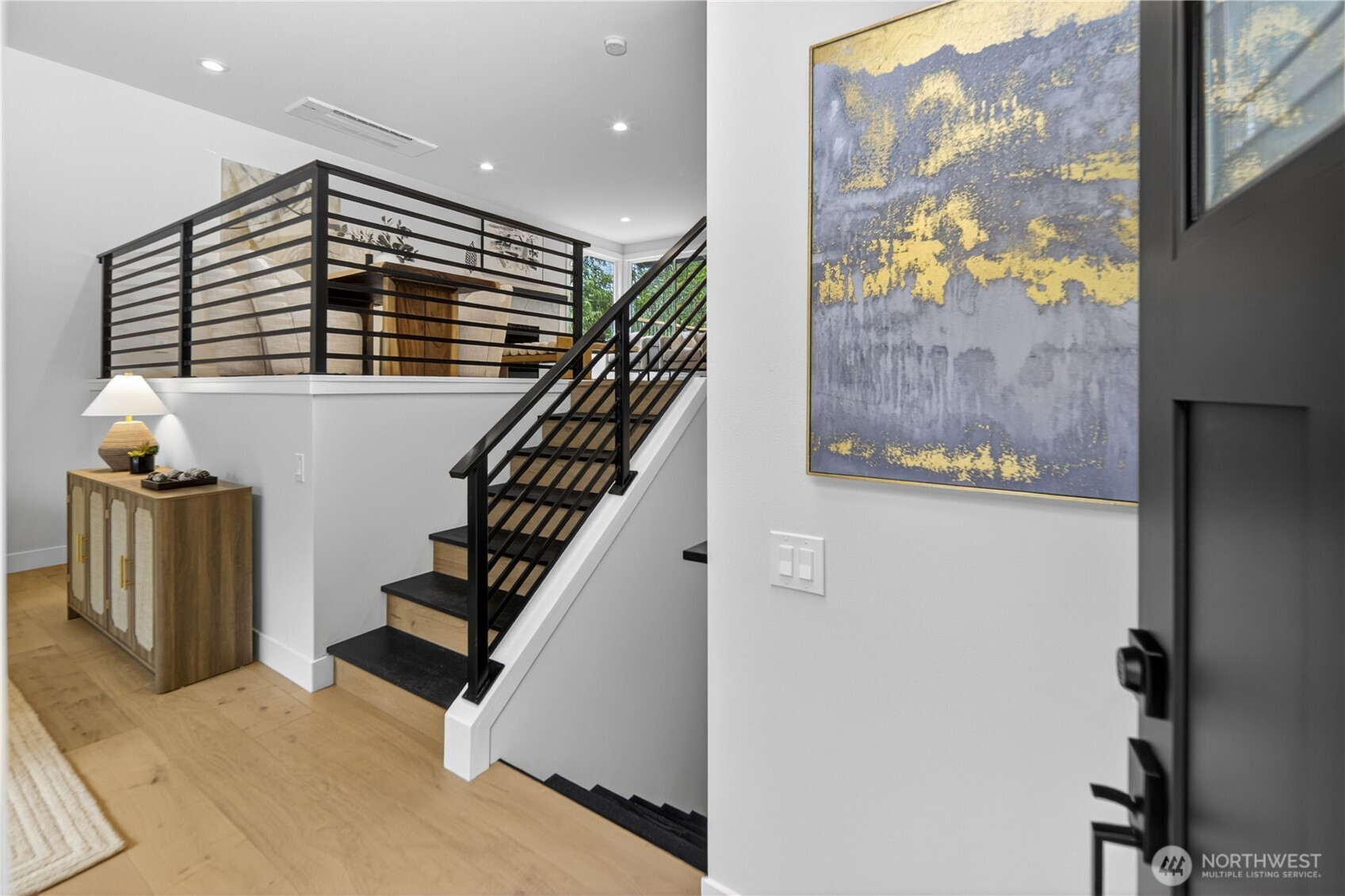 High ceilings, crisp white paint, modern linear railings, and luxury engineered hardwood floors create a fresh, uplifting welcome as you step inside. Warm natural-light bulbs in the recessed lighting give the home a soft, even glow throughout the home. New black interior trim details carry the Pacific Northwest-inspired exterior design inside, creating a cohesive modern look from the entry onward.