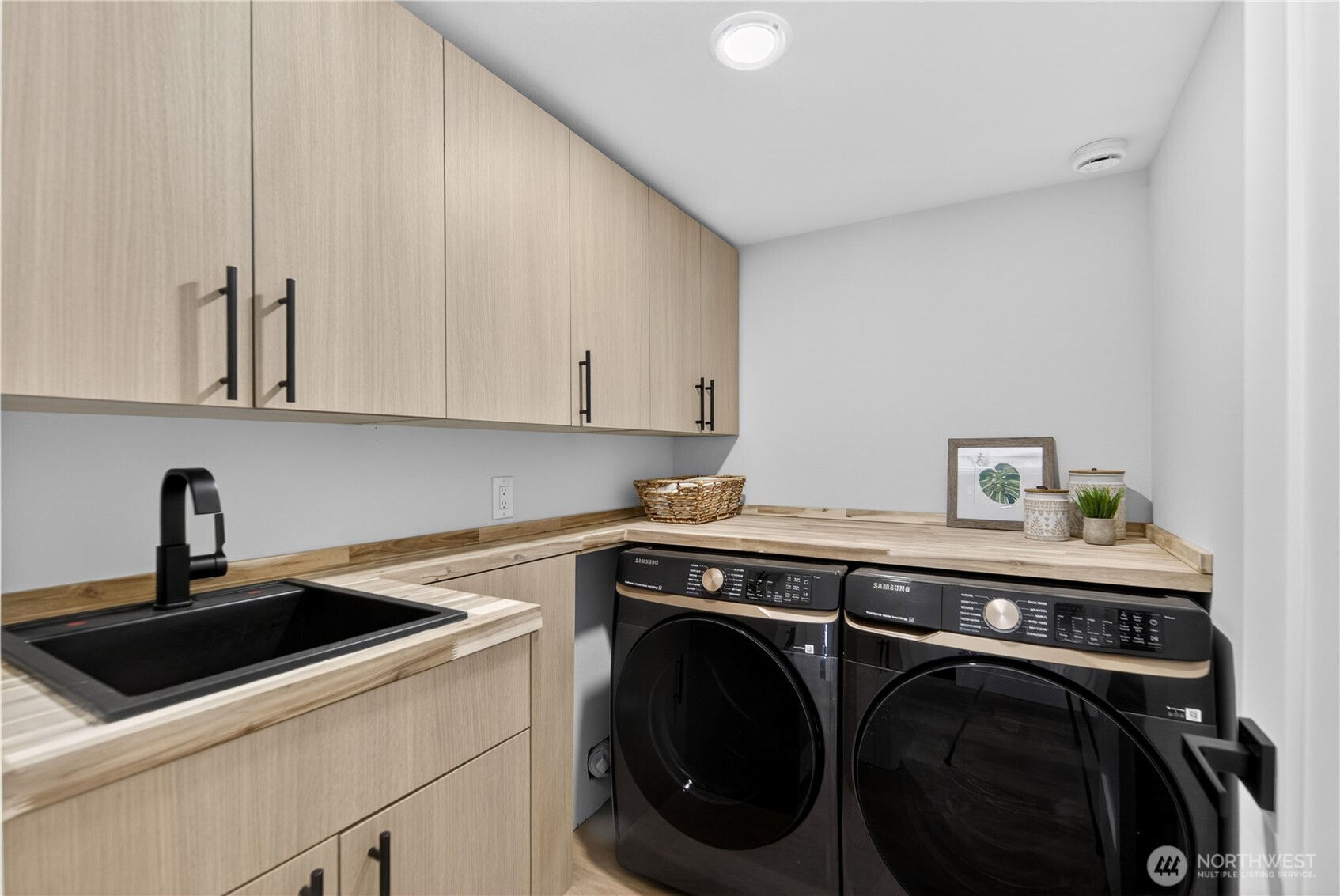 Even laundry feels elevated in this beautifully finished downstairs space, with full-size new Samsung front-load washer and dryer, cabinetry that matches the kitchen, and a warm butcher block-style counter just like the upstairs pantry. Sleek black cabinet handles add a refined designer touch, while the matching deep sink makes delicate washing, soaking, and rinsing easier. With room to fold, sort, and care for the little things, this laundry room turns a daily chore into a space that feels calm, organized, and unexpectedly lovely.