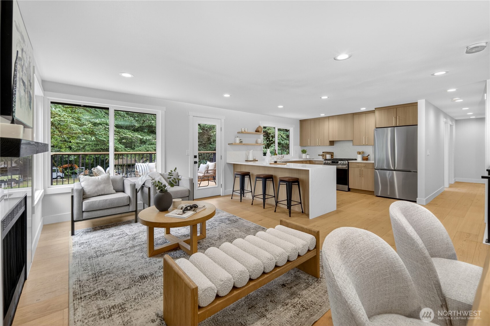 Large windows in the main living area draw in beautiful natural light all day and frame lovely views of the surrounding trees, while the door opens directly to the new expansive deck in the private back yard. The result is an easy, inviting connection between indoor living and the peaceful outdoor setting. As the day winds down, the southern exposure brings soft evening color into the room, with warm amber, lavender, and coral tones filtering through the trees.  All windows throughout the home are new double-pane storm windows, adding comfort and efficiency.
