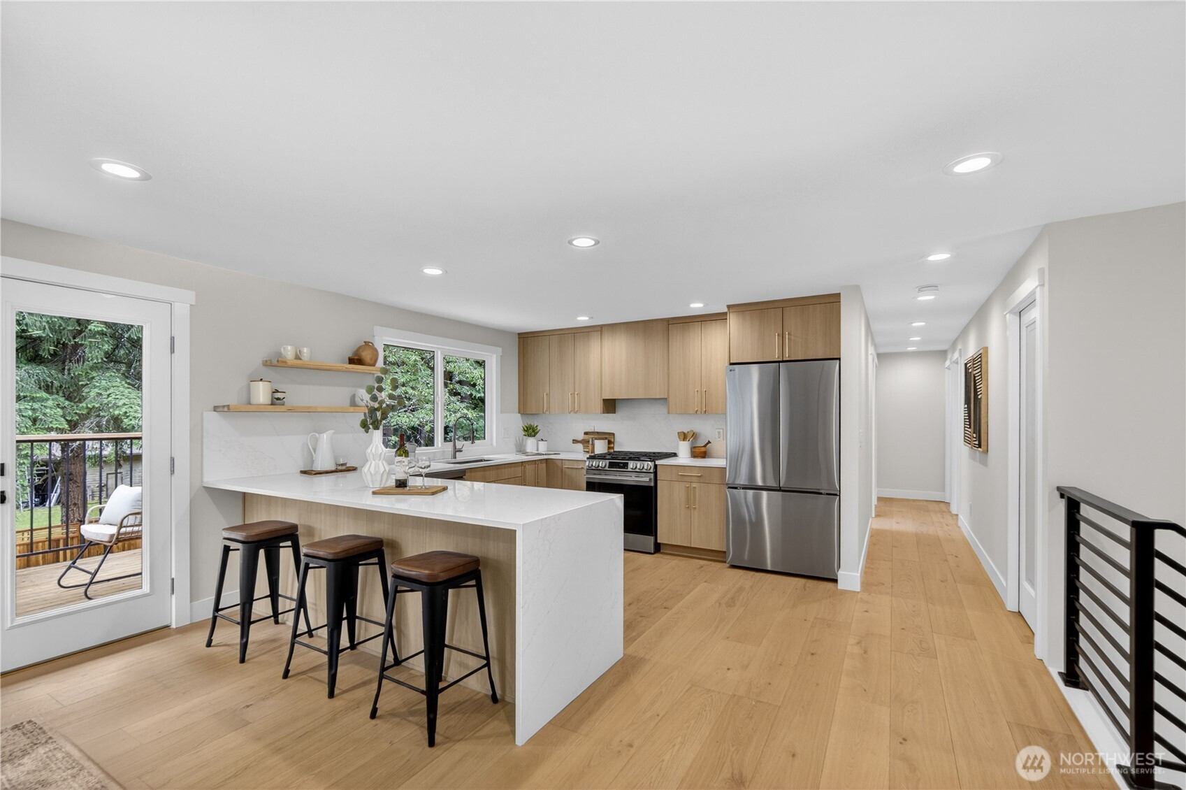 Marbled quartz slab counters give the kitchen a bright, polished beauty, with light, uplifting colors creating a cheerful place for the daily rhythm of cooking.  A full-height backsplash adds elegance and easy care, continuing behind the stove for a clean, seamless look. At the breakfast bar, the marbled quartz spills down the side in a waterfall edge, turning the island into a beautiful designer centerpiece.
