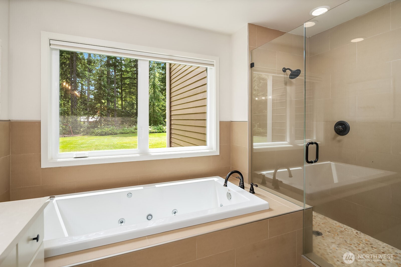 A luxurious jetted soaking tub and a large walk-in tile shower make this primary bath a true spa-like escape, with a garden-view window adding a serene, light-filled ambiance.