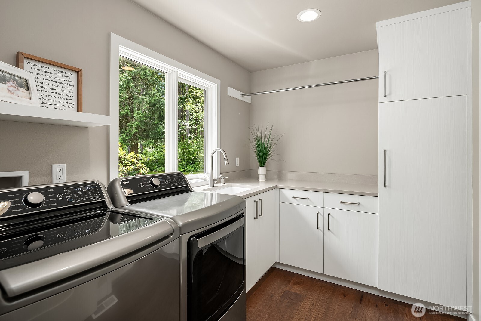 The conveniently located second-floor laundry room features ample cabinetry, a utility sink, and a bright window, making everyday chores effortless and organized.