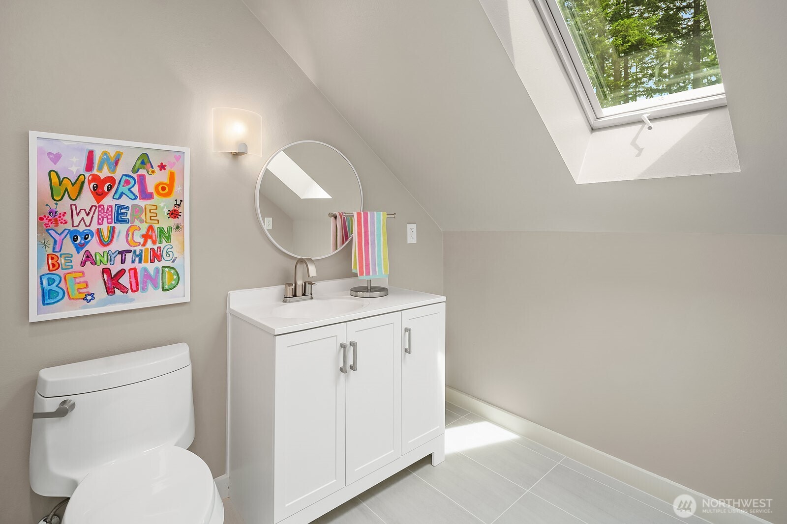 A skylit bathroom serves the bonus room level, featuring a clean white vanity and plenty of natural light, adding everyday convenience to this fun and functional upper space.