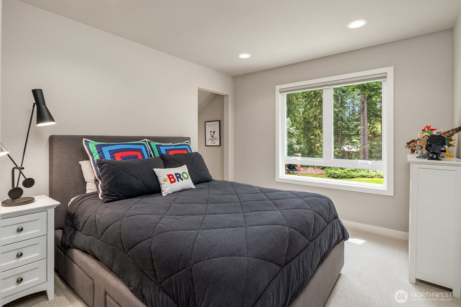 One of four spacious upstairs bedrooms offers a comfortable and well-appointed retreat with large windows framing peaceful wooded views and plenty of room for rest and relaxation.
