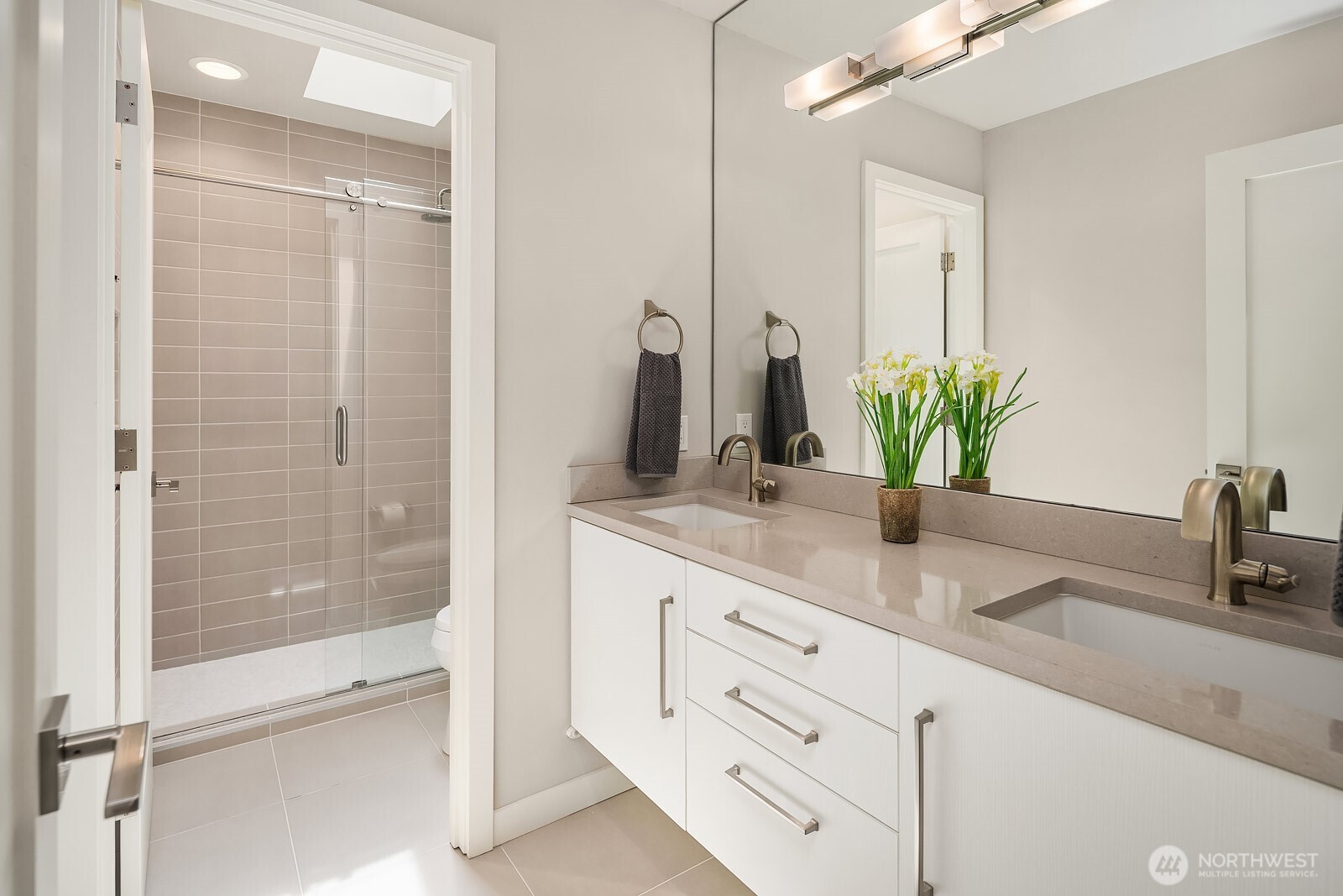 The updated hall bath features a walk-in tile shower, white cabinetry, and modern finishes, offering a fresh and functional space to serve the upstairs bedrooms.