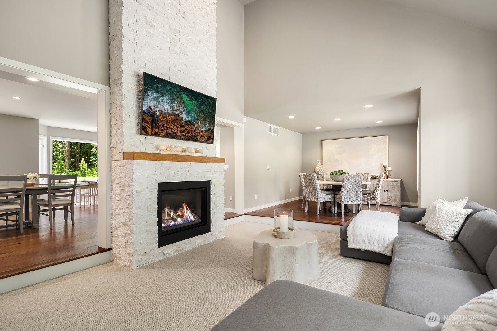 The open-concept great room impresses with soaring ceilings and a dramatic floor-to-ceiling fireplace, creating a warm and inviting centerpiece for everyday living and entertaining.