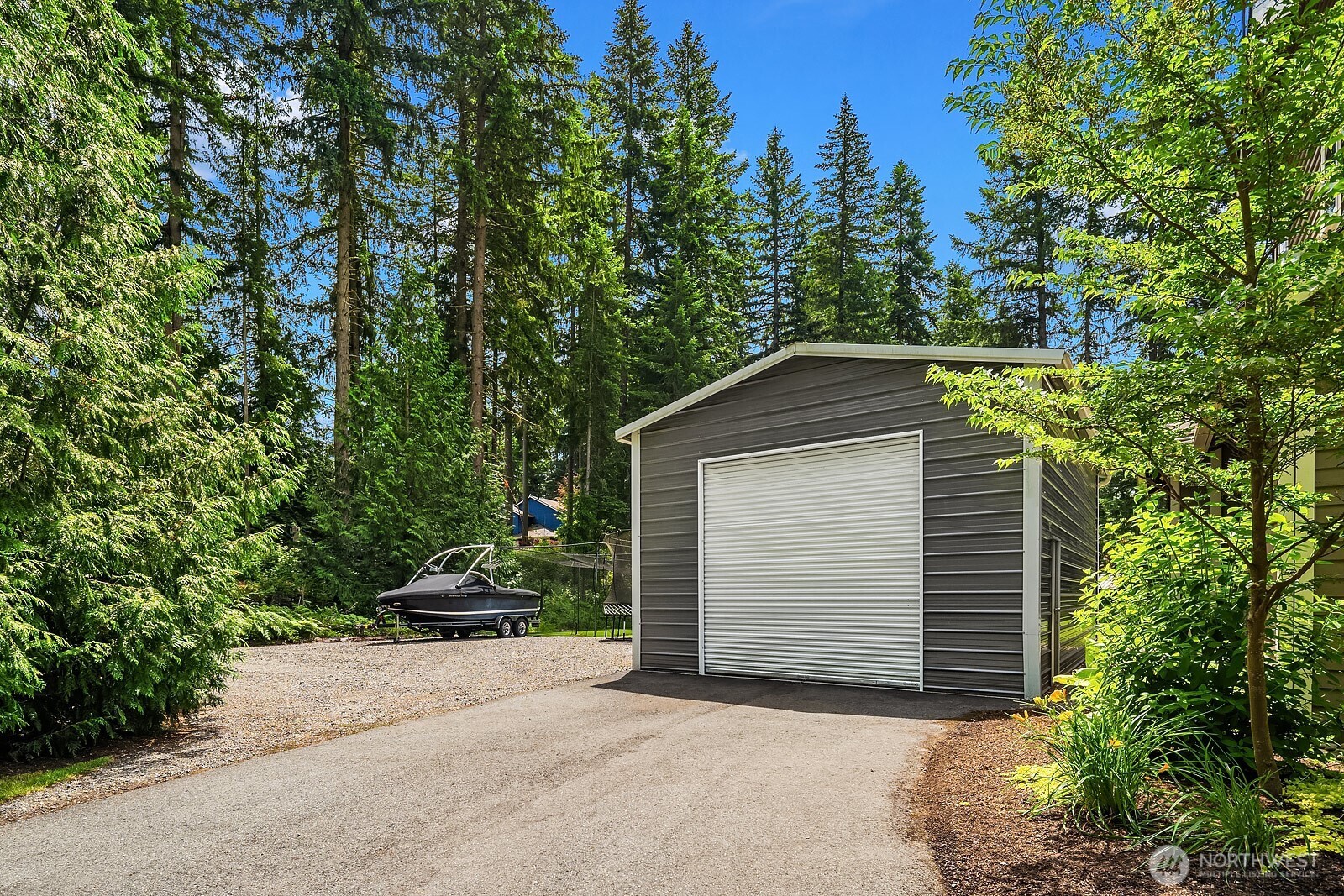 The 19x30 detached shop features a 10-foot door and EV hookup, providing ample space for vehicles, equipment, hobbies, or storage tucked privately among the trees.