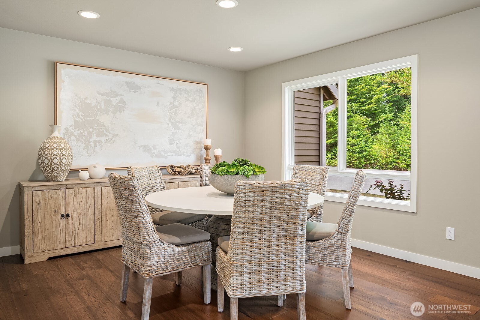 The bright and airy dining space features rich hardwood floors and large windows that flood the room with natural light, flowing seamlessly into the living areas for effortless entertaining.