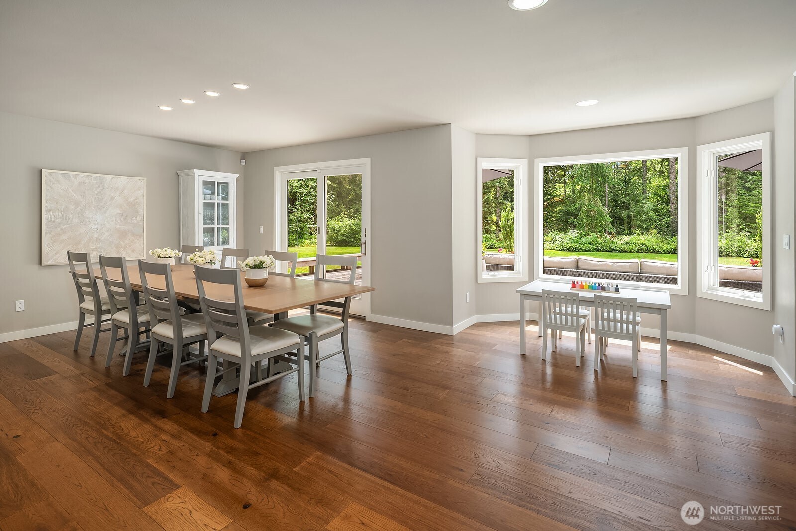 The spacious dining area offers generous room for a large table and flows directly to the walls of windows overlooking the secluded backyard, bringing the beauty of the private wooded setting inside.