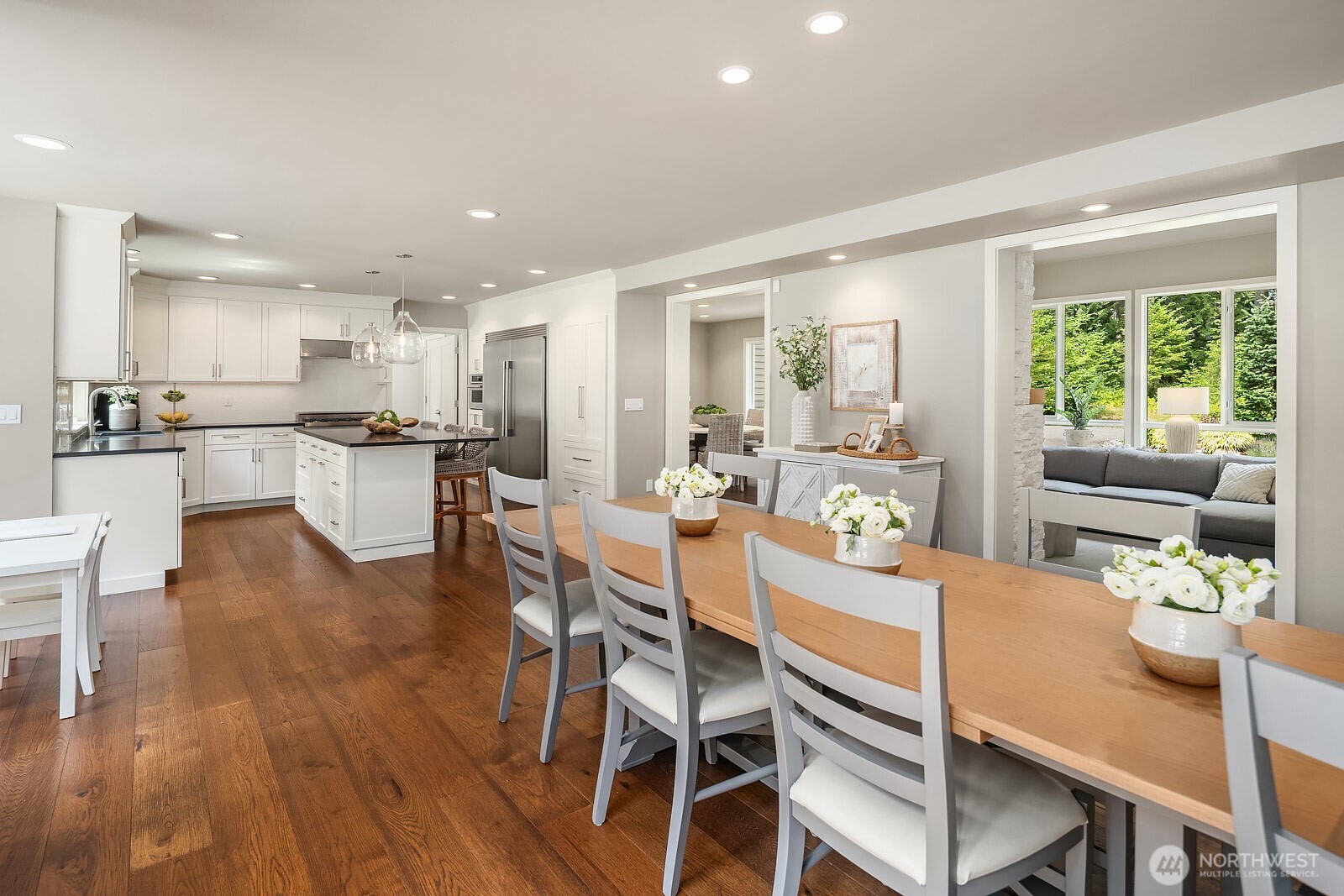 This view captures the seamless connection between the dining area and the updated kitchen, showcasing the open-concept layout, rich hardwood floors, and bright white cabinetry that give the home its refined, move-in ready feel.