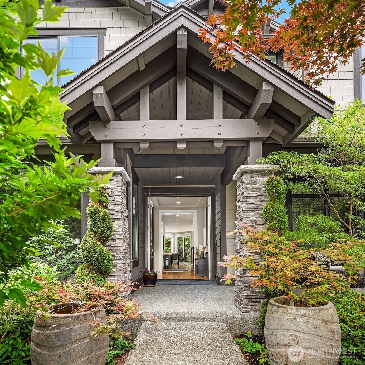 Impressive craftsman entryway framed by soaring timber beams and lush mature greenery, creating a grand yet welcoming first impression. The covered front porch and striking double doors set the tone for the refined living found throughout this exceptional home.