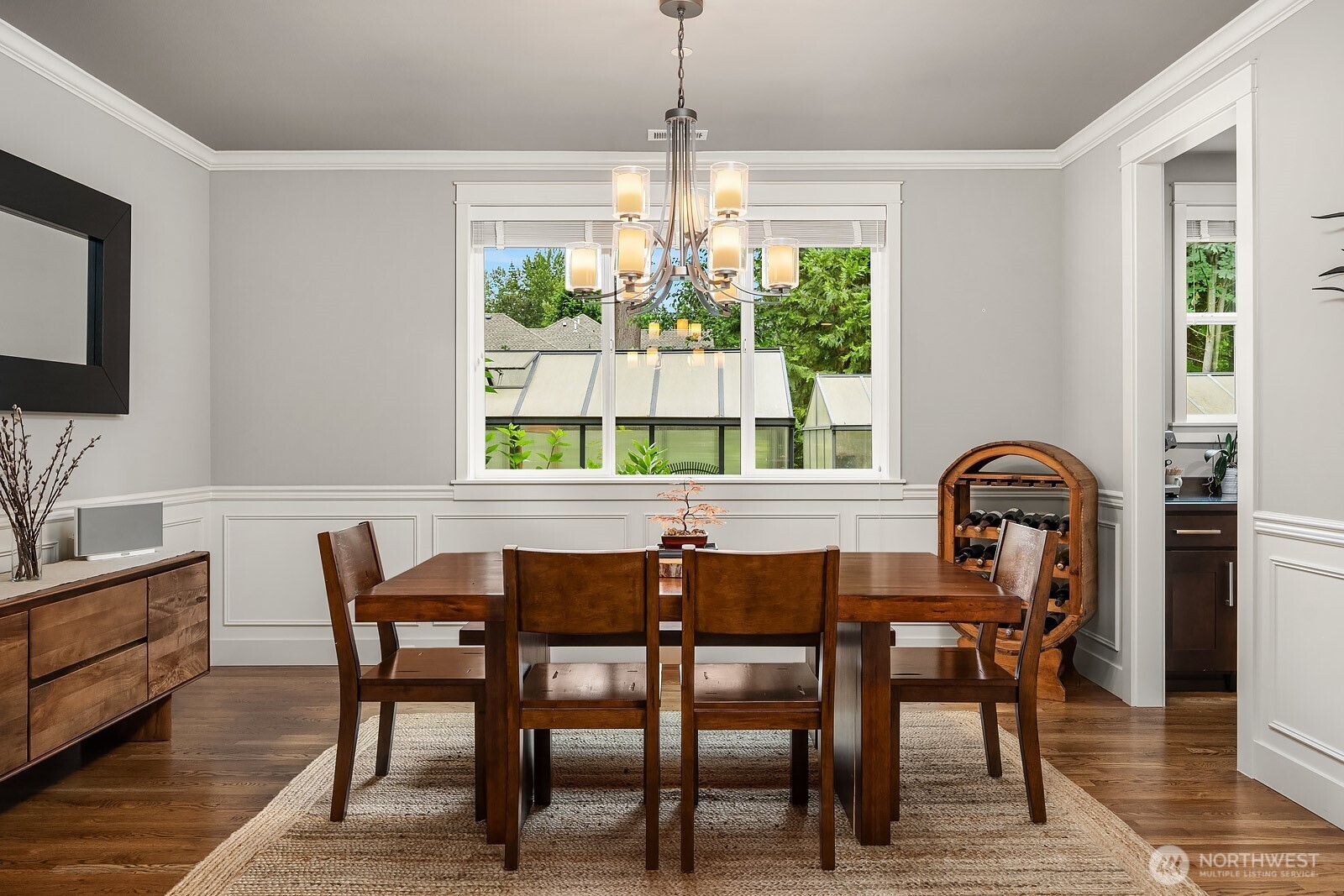 The formal dining room exudes timeless elegance with classic wainscoting, a refined chandelier, and warm hardwood floors perfect for hosting memorable gatherings. Bright windows overlook the lush grounds, filling the space with natural light and a connection to the beautiful outdoors.