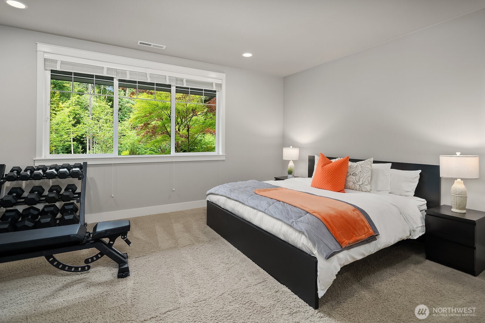 The main level guest suite offers a comfortable and private retreat with plush carpet, generous proportions, and a bright window framing lush outdoor views. A walk-in closet and private ensuite make this space ideal for overnight guests or multi-generational living.