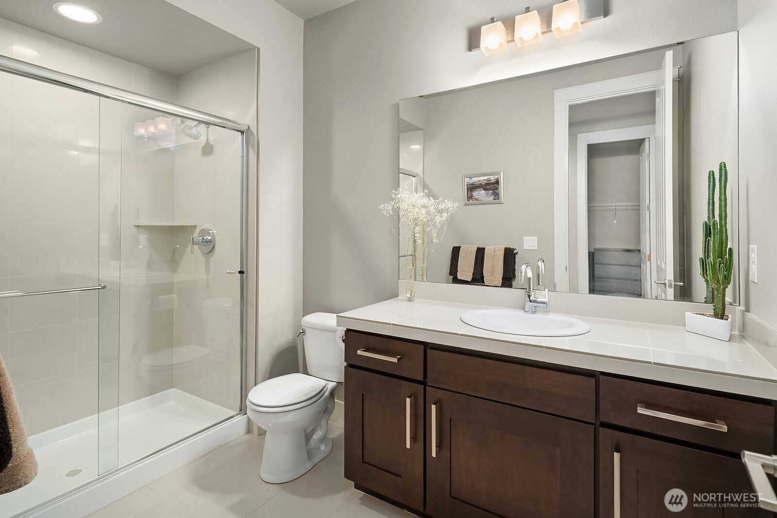 The main level guest ensuite features a sleek walk-in shower, rich dark vanity cabinetry, and clean modern finishes that provide a private and polished experience for guests.