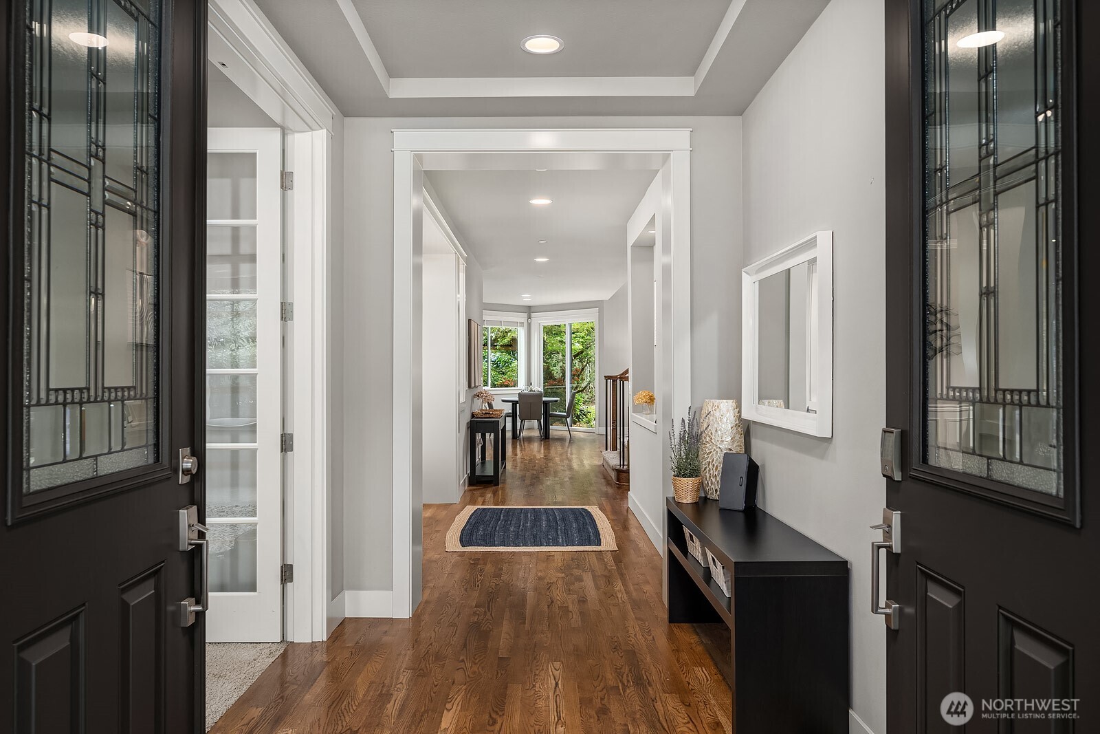 Gleaming hardwood floors and soaring ceilings welcome you into the main level, with an elegant foyer that flows seamlessly toward the heart of the home. Crisp white millwork and an abundance of natural light create a bright, sophisticated entry experience.