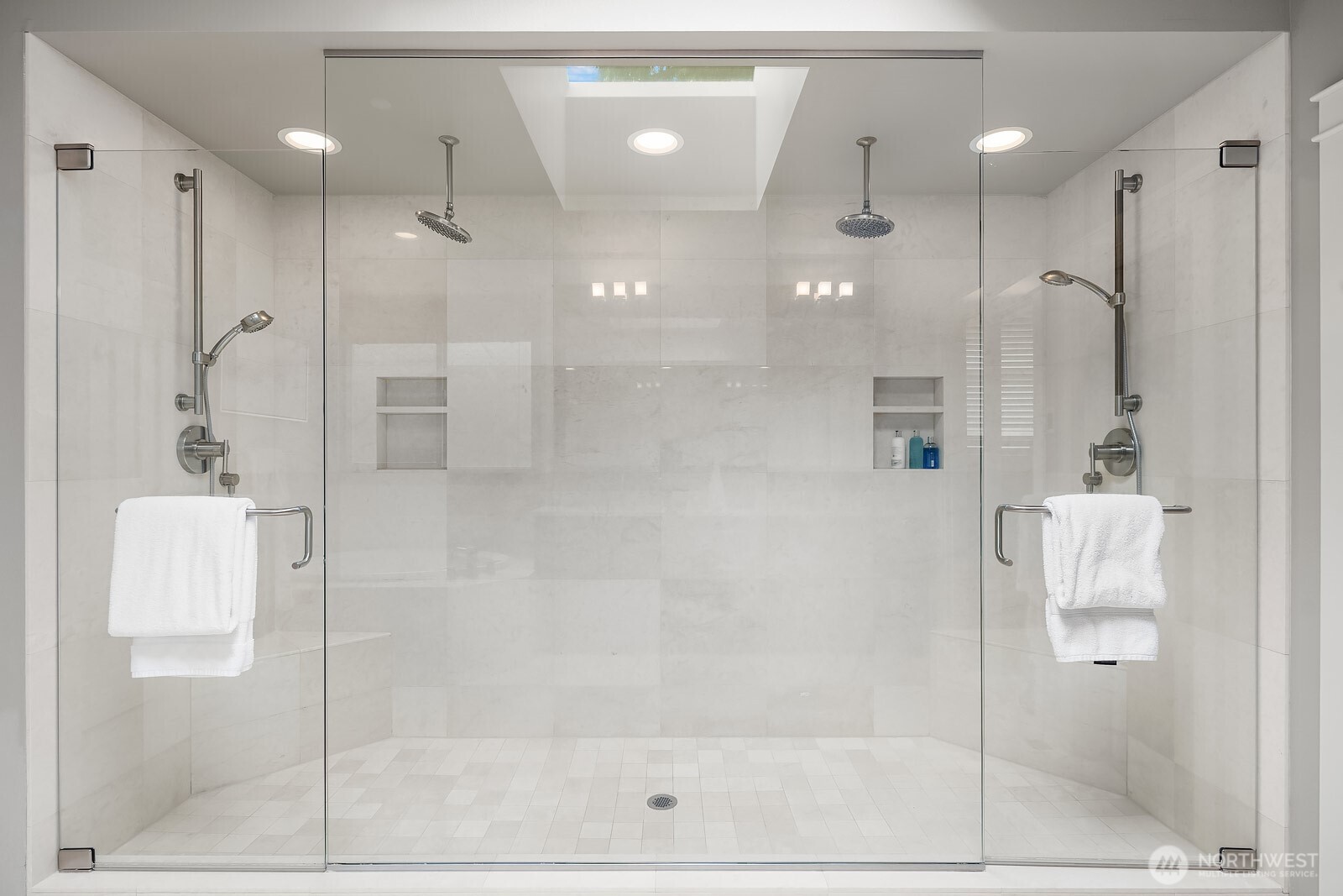 The primary ensuite's extraordinary dual shower enclosure is finished in floor-to-ceiling marble-look tile, offering a truly resort-caliber experience rarely found in residential homes.
