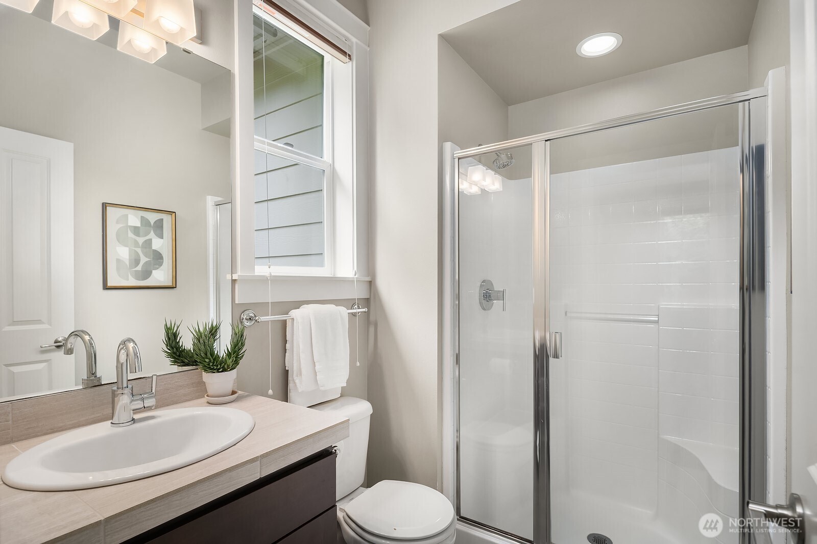 This additional upper level bathroom features a walk-in shower, elegant dark vanity cabinetry, and refined finishes, ensuring every bedroom on this level is well-served with quality accommodations.