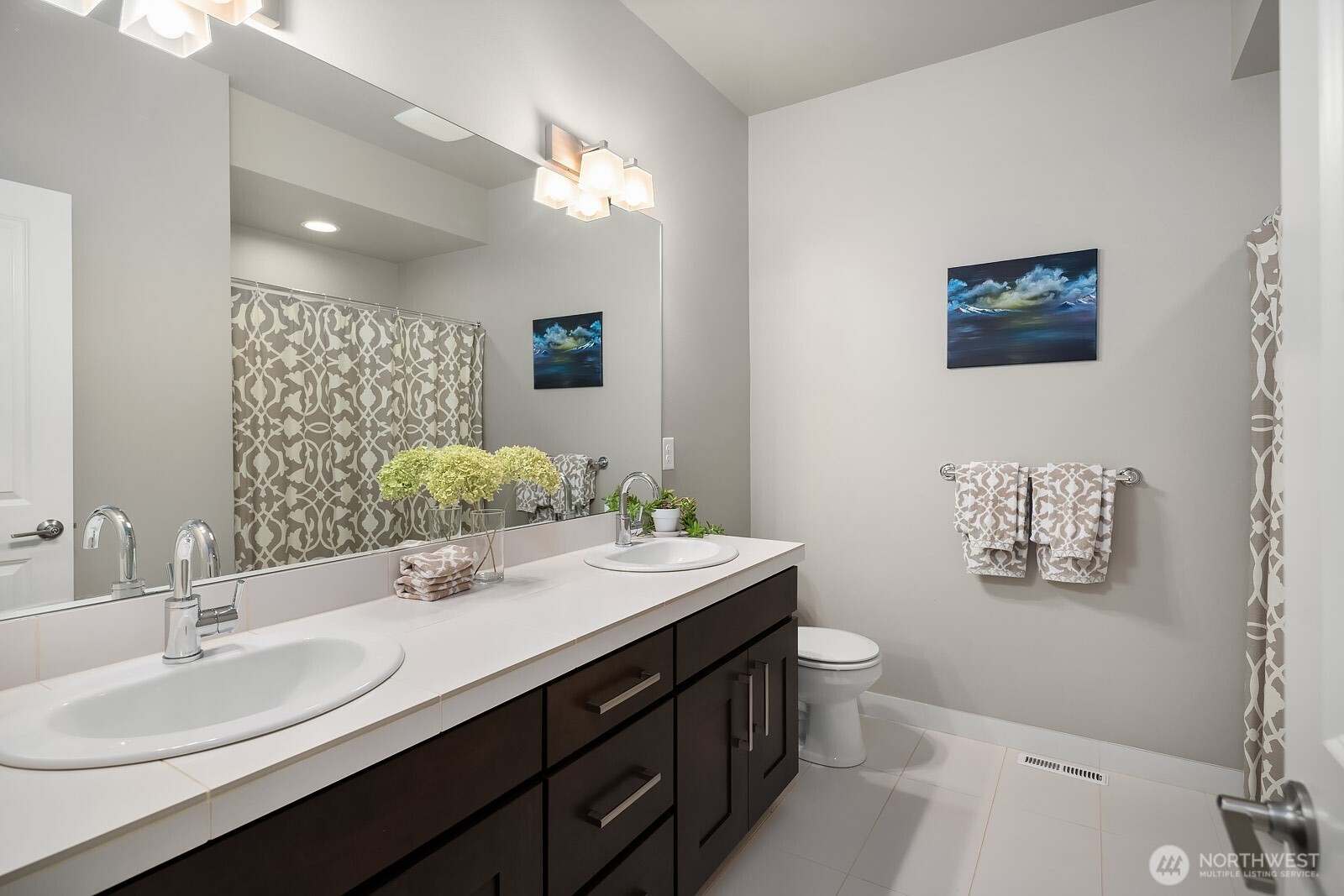 This well-appointed upper level bathroom features a generous dual-sink vanity with dark cabinetry, stylish tile accents, and polished finishes that serve the surrounding bedrooms beautifully.