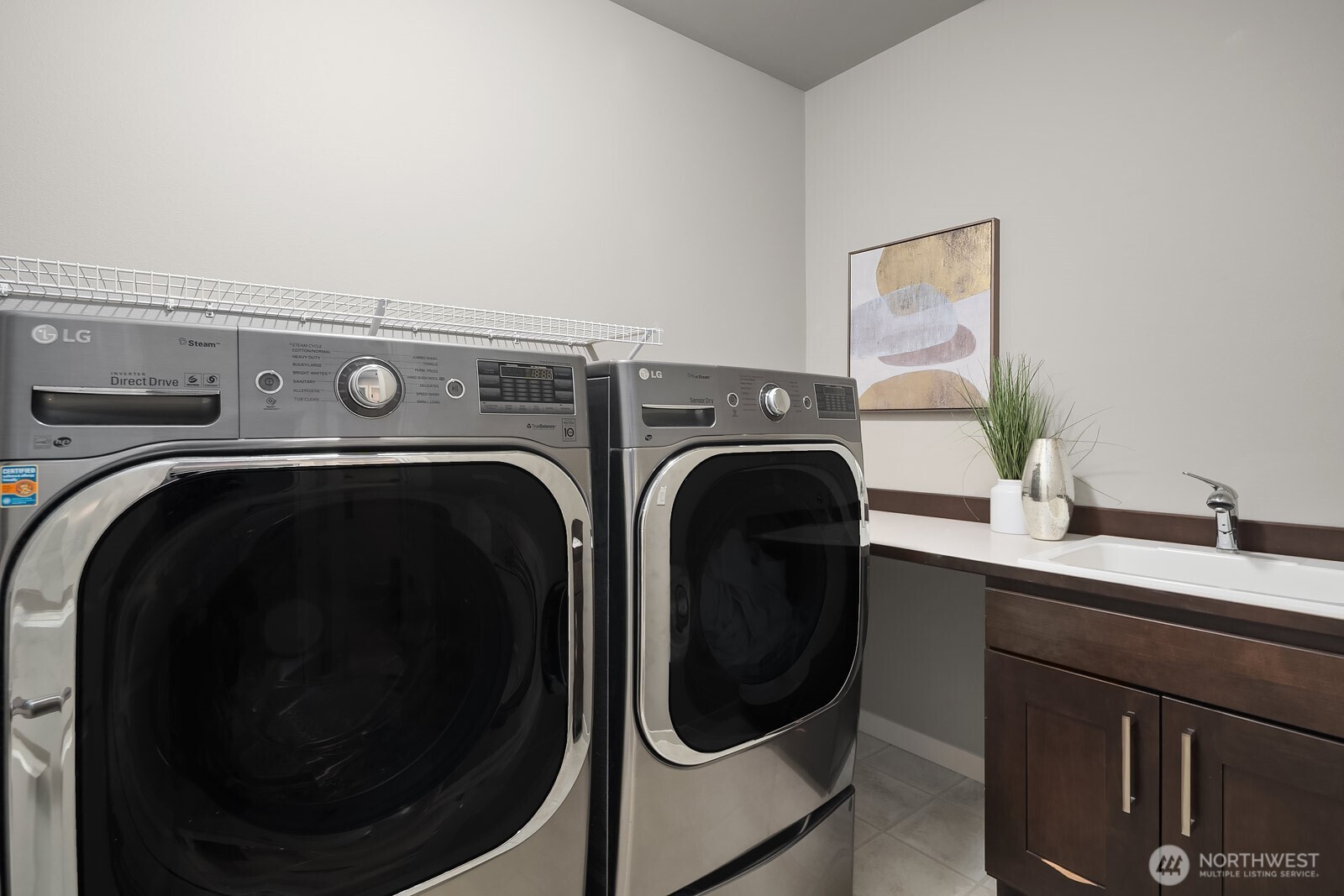 A dedicated laundry room features premium side-by-side washer and dryer, dark cabinetry for added storage, and a clean, functional layout that makes everyday tasks a breeze.